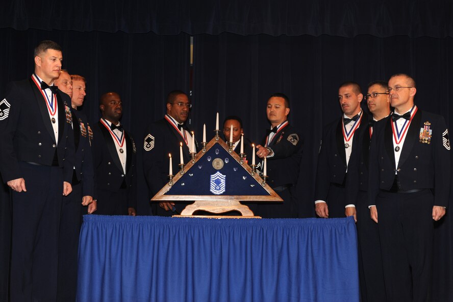 Senior Master Sgt. Michael Martinez, 56th Aircraft Maintenance Squadron, lights a candle as other inductees gather around the candle stand. Each candle represents an enlisted grade in the U.S. Air Force up to chief master sergeant.  (U.S. Air Force photo by Airman 1st Class Devante Williams)