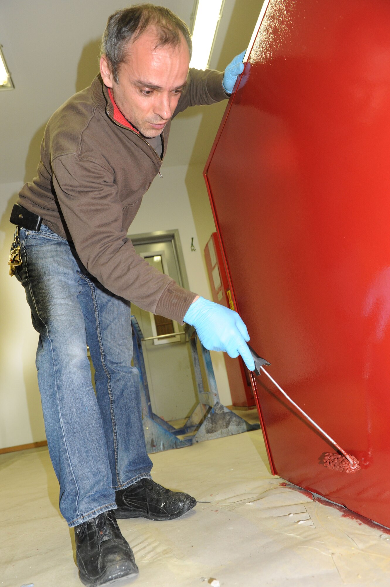 SPANGDAHLEM AIR BASE, Germany – Achim Elsen, 52nd Civil Engineer Squadron painter, uses a paint brush to roll paint on a metal cabinet in the paint shop at Bldg. 120 here Feb 14. Elsen, along with seven other painters, maintains paint for the flightline, road markings, traffic signs, parking lots, government buildings, signs and other items needed for base special events. Painting visible and up-to-date signs and road markings helps the base stay safe. This makes road markings visible from a further distance keeping traffic flow orderly and safe.  (U.S. Air Force photo by Senior Airman Christopher Toon/Released)