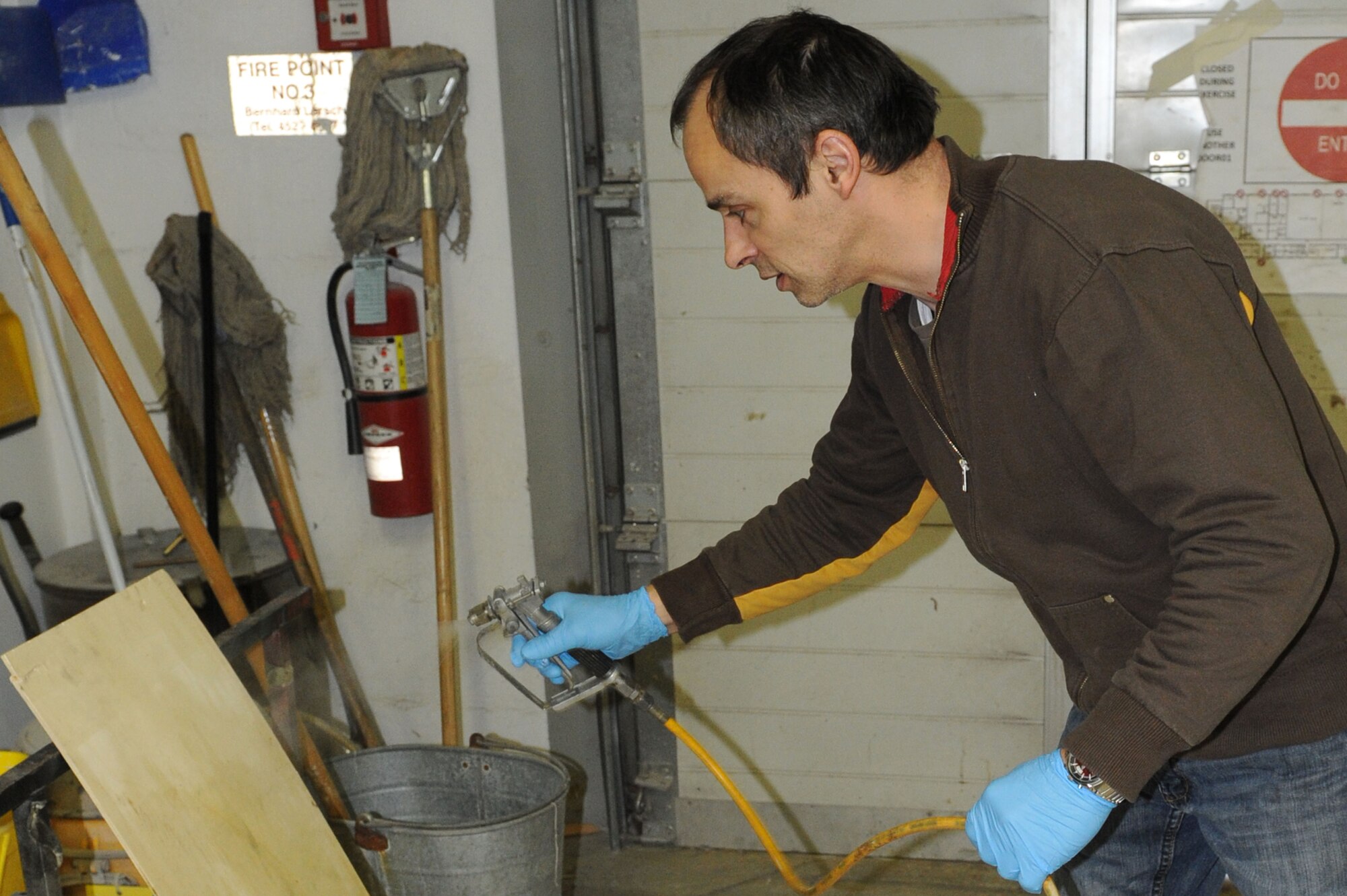 SPANGDAHLEM AIR BASE, Germany – Achim Elsen, 52nd Civil Engineer Squadron painter, uses a paint air gun to spray primer on a piece of wood in the paint shop at Bldg. 120 here Feb 14. Elsen, along with seven other painters, maintains paint for the flightline, road markings, traffic signs, parking lots, government buildings, signs and other items needed for base special events. Painting visible and up-to-date signs and road markings helps the base stay safe. This makes road markings visible from a further distance keeping traffic flow orderly and safe. (U.S. Air Force photo by Senior Airman Christopher Toon/Released)