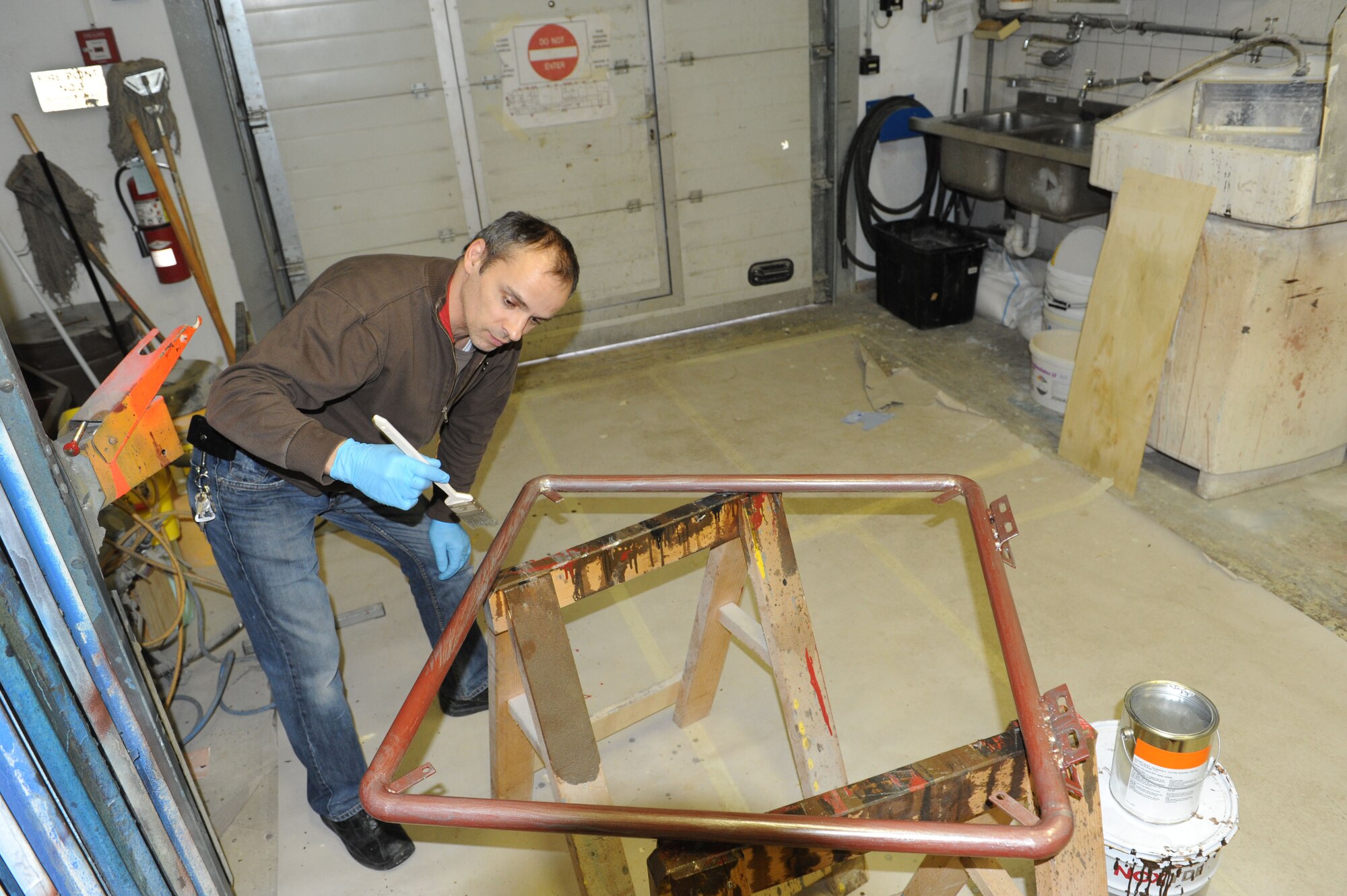 SPANGDAHLEM AIR BASE, Germany – Achim Elsen, 52nd Civil Engineer Squadron painter, paints a metal frame in the paint shop at Bldg. 120 here Feb 14. Elsen, along with seven other painters, maintains paint for the flightline, road markings, traffic signs, parking lots, government buildings, signs and other items needed for base special events. Painting visible and up-to-date signs and road markings helps the base stay safe. This makes road markings visible from a further distance keeping traffic flow orderly and safe.  (U.S. Air Force photo by Senior Airman Christopher Toon/Released)