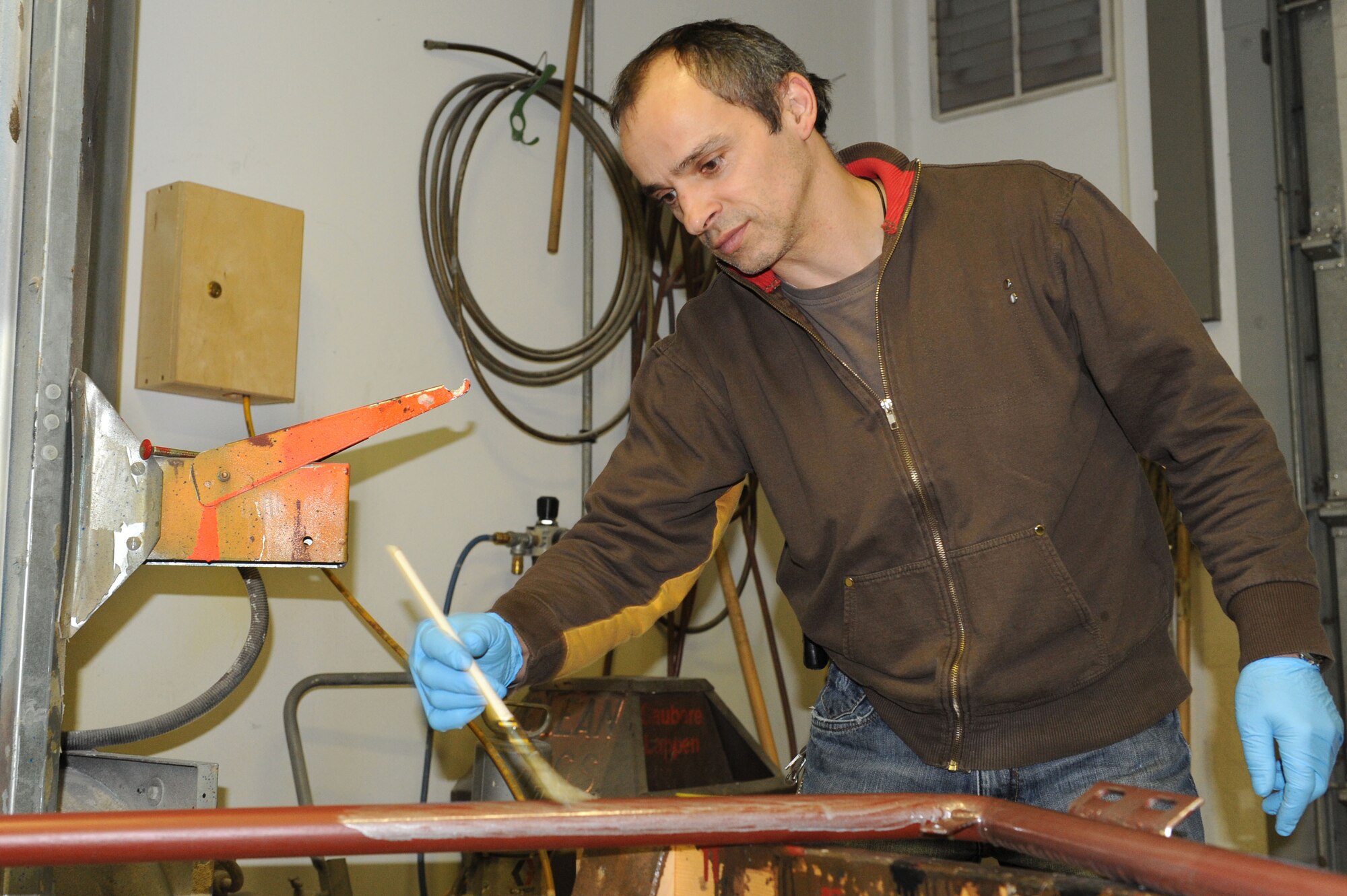 SPANGDAHLEM AIR BASE, Germany – Achim Elsen, 52nd Civil Engineer Squadron painter, paints a metal frame in the paint shop at Bldg. 120 here Feb 14. Elsen, along with seven other painters, maintains paint for the flightline, road markings, traffic signs, parking lots, government buildings, signs and other items needed for base special events. Painting visible and up-to-date signs and road markings helps the base stay safe. This makes road markings visible from a further distance keeping traffic flow orderly and safe. (U.S. Air Force photo by Senior Airman Christopher Toon/Released)