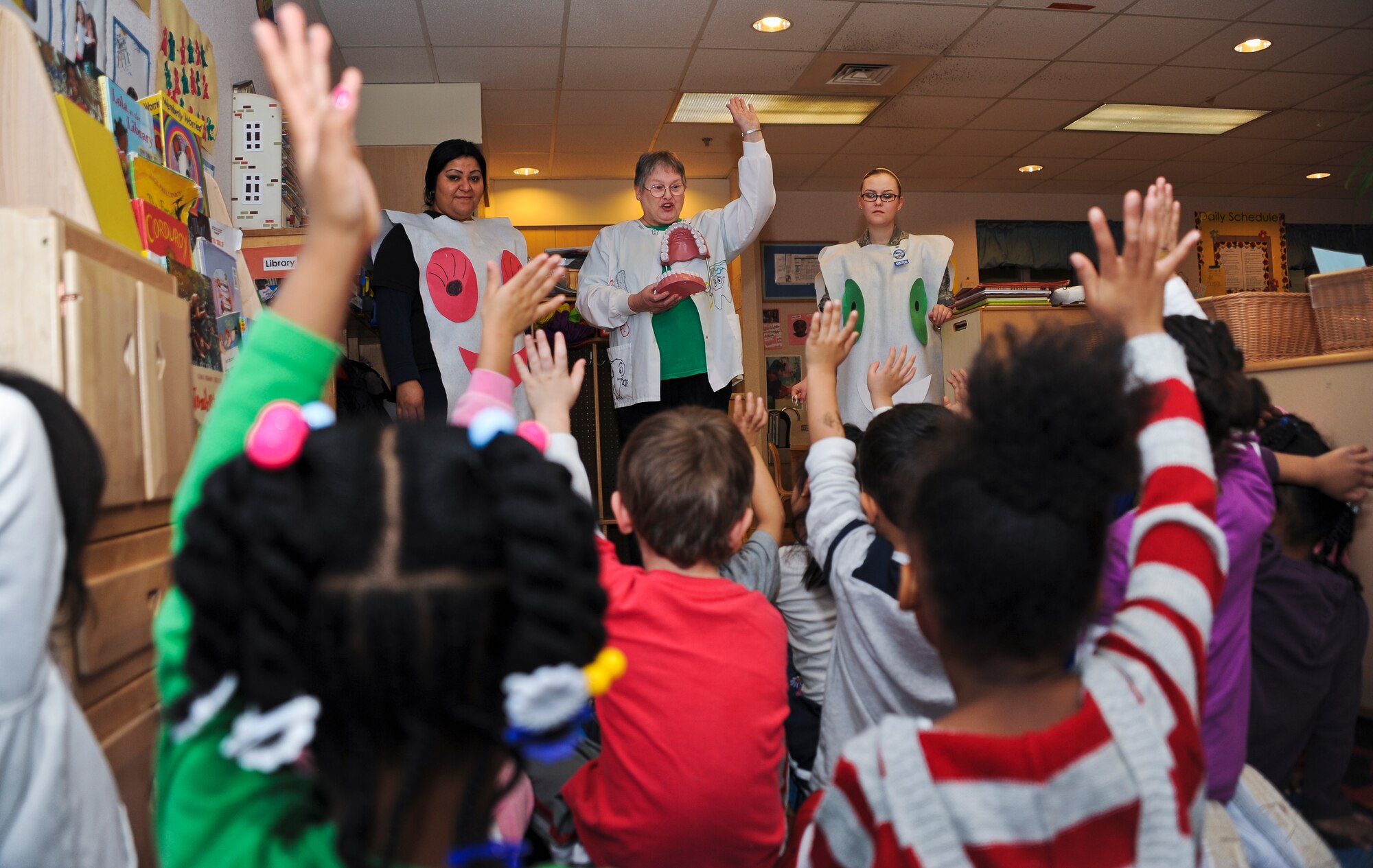 Children enrolled at the Child Development Center on base raise their hands Feb. 15 to answer the question “how many times do you brush your teeth a day?” Airmen and civilians from the 87th Dental Squadron taught children at the CDC the importance of proper oral hygiene in honor of National Children’s Dental Health Month. (U.S. Air Force photo by Airman 1st Class Dennis Sloan/Released)