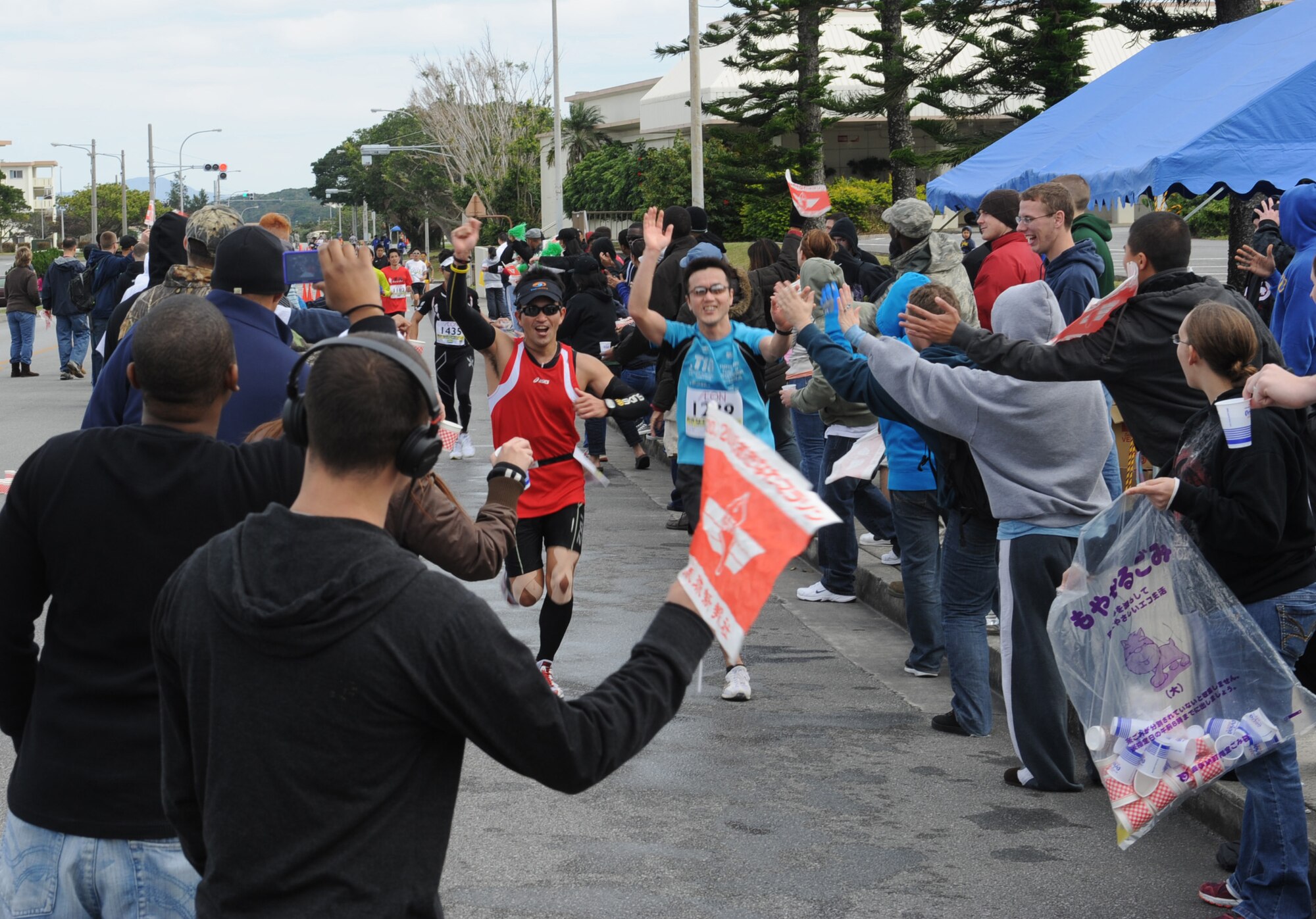 Participants of the 2012 Okinawa Marathon run through a cheering crowd on Kadena Air Base, Japan, Feb. 20, 2012. More than 200 base volunteers handed out water and cheered on participants before they made their way out Gate 5 toward the final stretch of the marathon.  (U.S. Air Force photo by Airman 1st Class Justin Veazie/Released) 