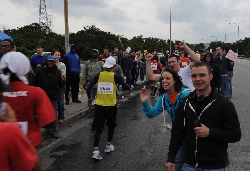 Kadena Air Base volunteers cheer on the 2012 Okinawa Marathon runners as they head towards Gate 5 on Kadena Air Base, Japan, Feb. 20, 2012. More than 200 base volunteers handed out water and cheered on participants before they made their way out Gate 5 toward the final stretch of the marathon.  (U.S. Air Force photo by Airman 1st Class Justin Veazie/Released) 