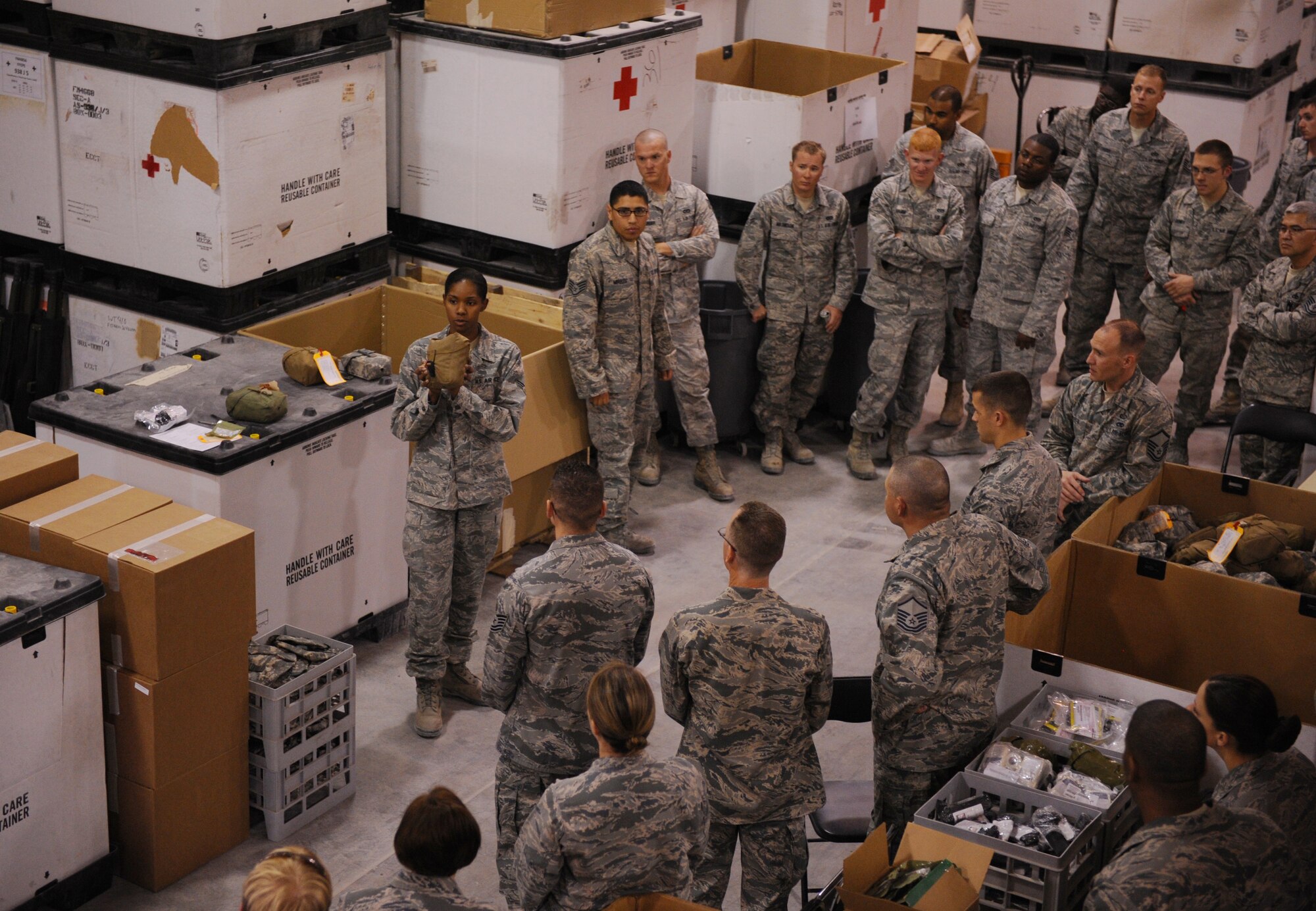 SOUTHWEST ASIA – Senior Airman Letichia Blue, 379th Expeditionary Medical Group medical logistics technician and native of Alexandria, Va., explains how to pack an individual first aid kit to volunteers here Feb. 14, 2012. The medical logistics warehouse depends on volunteers, who recertify about 35,000 IFAKs every year. (U.S. Air Force photo/Staff Sgt. Nathanael Callon)