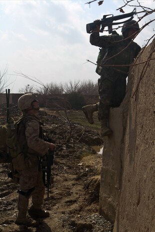 Cpl. Michael Greenleaf, a radio operator with 3rd Platoon, India Company, 3rd Battalion, 7th Marine Regiment, helps his Afghan National Army, counterpart scale a wall, during an Afghan led, partnered patrol, Feb. 20. India Company mentored and trained the ANA to take more responsibility while on patrols. The Afghans soldiers, stationed with India Company, patrols alone regularly. The ANA patrolled through an area south of the patrol base, known for insurgent activites.