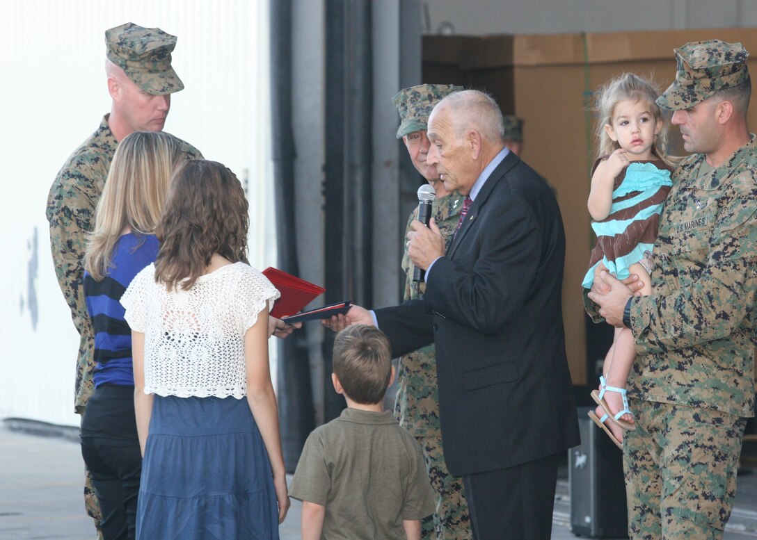 Mr. Mike DiFrancesco, director of Marine Corps Law Enforcement Foundation gives Staff Sgt. Thomas J. Dudley's children $30,000 in financial aid, at the Marine Medium Tiltrotor Squadron 264 hangar, Nov. 7.