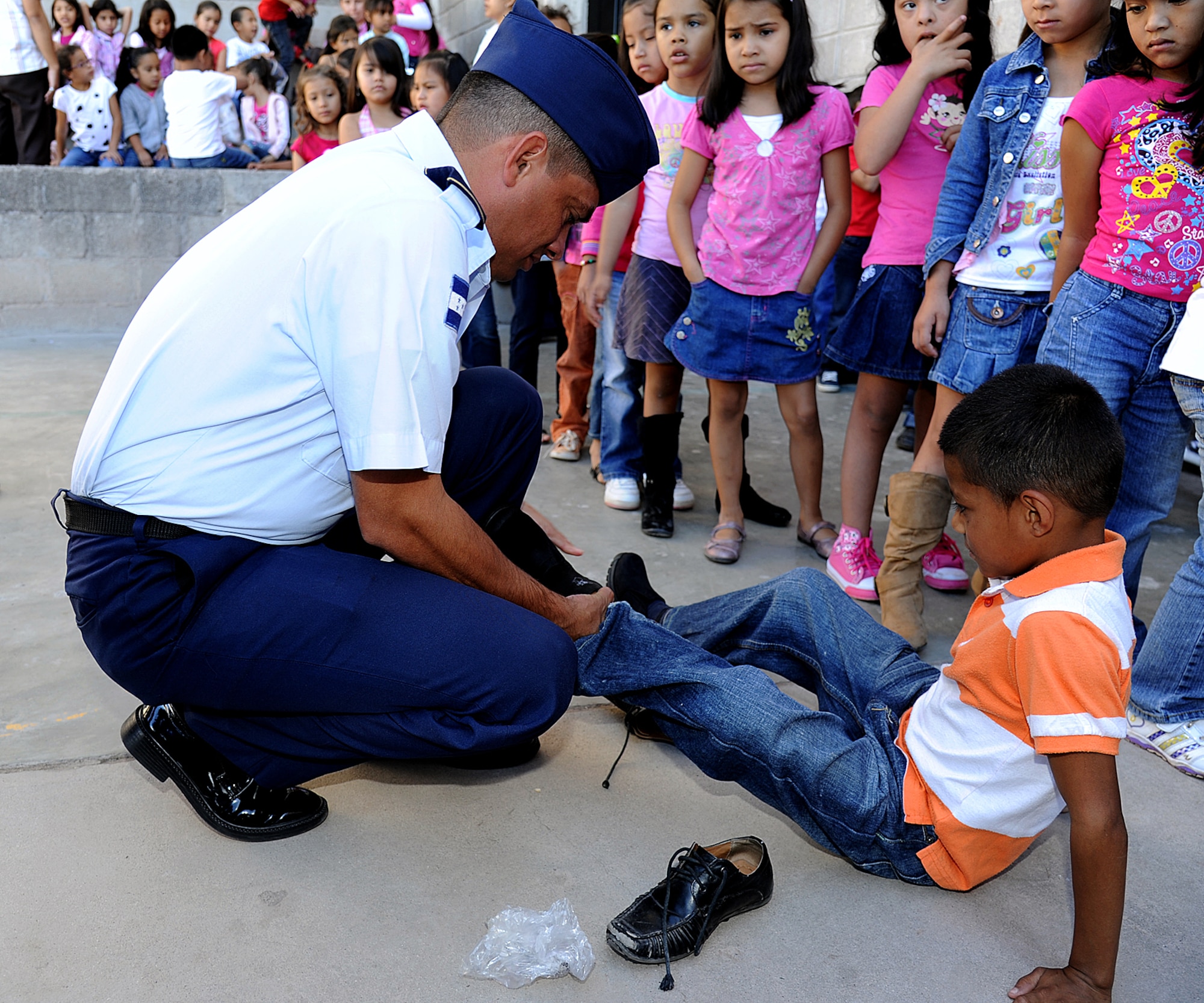 A Honduran Air Force Airman helps a student at the Instituto Evangélico El Verbo put on new shoes donated to the Honduran Air Force Feb. 17.  The 571st Mobility Support Advisory Squadron, based out of Travis AFB, Calif., have been working side-by-side with the Honduran Air Force promoting regional stability by fostering key relationships and enhancing partner nation capabilities. (U.S. Air Force photo by Tech. Sgt. Lesley Waters)