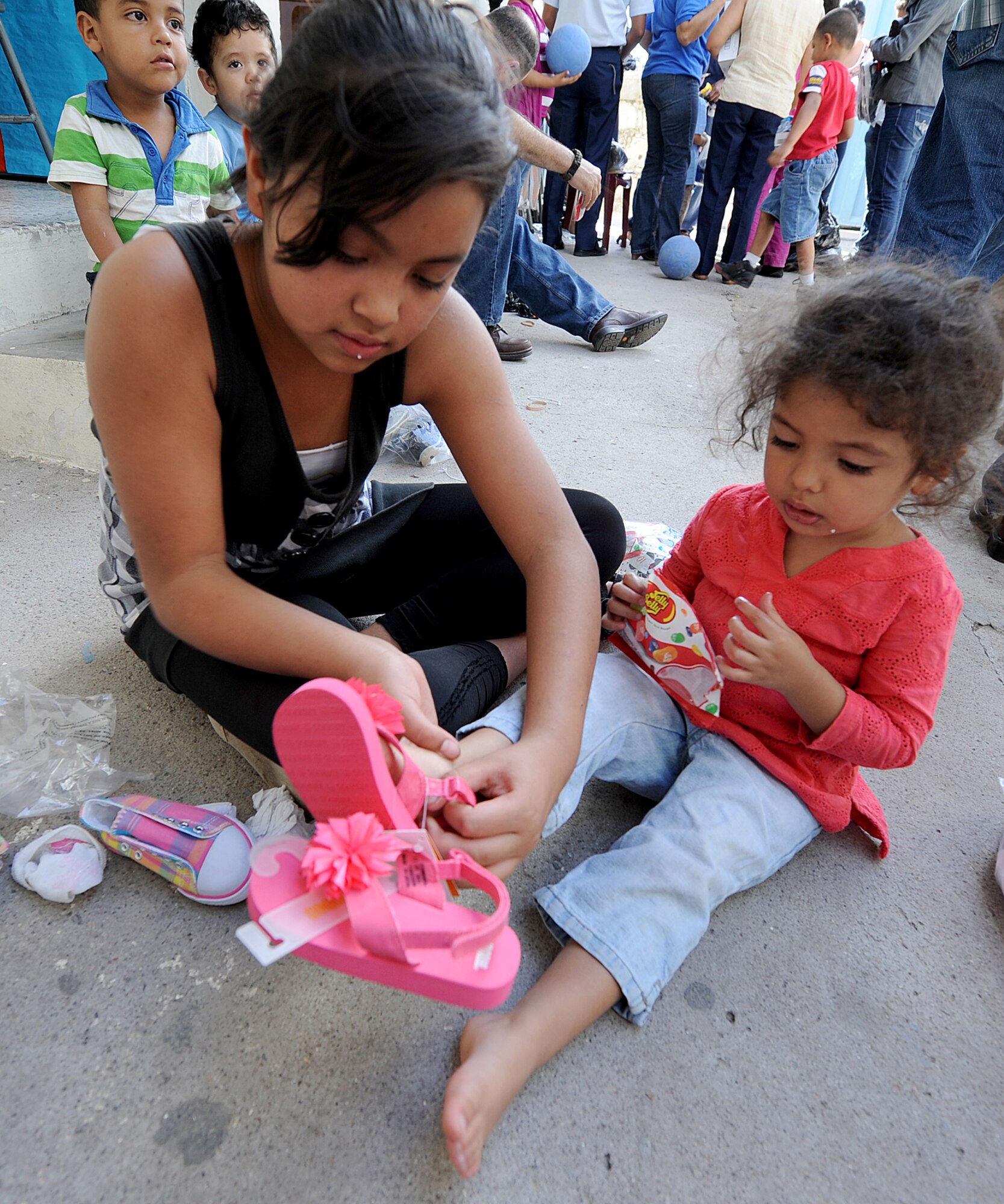 A teenager at the Instituto El Cordero helps another girl try on a new pair of sandals the Honduran Air Force delivered, with the help of the 571st Mobility Support Advisory Squadron, to the institute, in Tegucigalpa, Honduras, Feb. 14.  The Instituto El Cordero, sponsored by Association for World Services, is a school for children from single mothers.  (U.S. Air Force photo by Tech. Sgt. Lesley Waters)