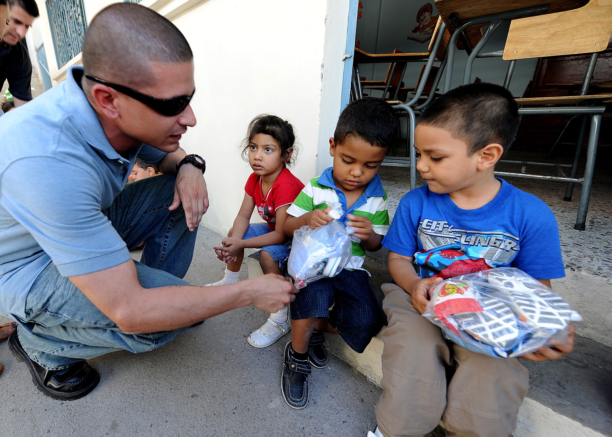 Staff Sgt. Jason Lares, 571st Mobility Support Advisory Squadron supply air advisor, works with the Honduran Air Force and hands out clothes to children at the Instituto El Cordero, in Tegucigalpa, Honduras, Feb. 14.  The Instituto El Cordero, sponsored by Association for World Services, is a school for children from single mothers.  (U.S. Air Force photo by Tech. Sgt. Lesley Waters)