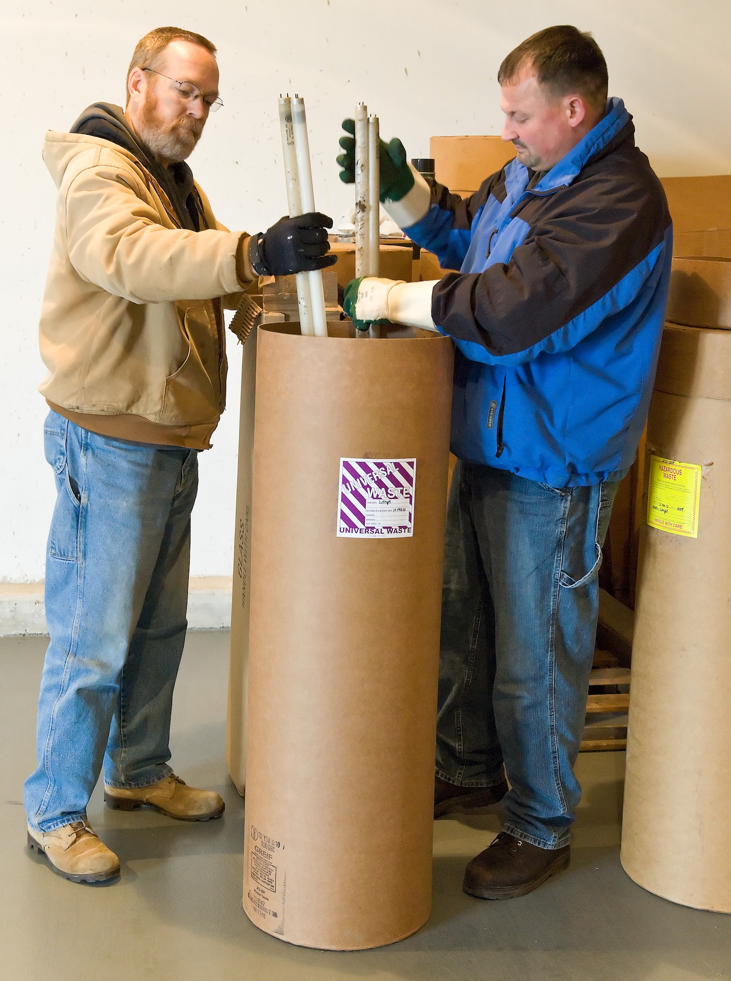 Deral Freysinger, Hazardous Waste Manager, with the 436th Civil Engineering Squadron, and Michael Shehorn, a contractor with Northwind Engineering, places used high intesity lamps in appropriate containers at the Central Hazardous Waste 90-Day Accumulation Point, February 16, 2012, Dover Air Force Base, Delaware. Freysinger and Shehorn collected and separated various types of high intensity lamps at building 1306, prepared and stored them for pick up. (U.S. Air Force photo by Roland Balik)
