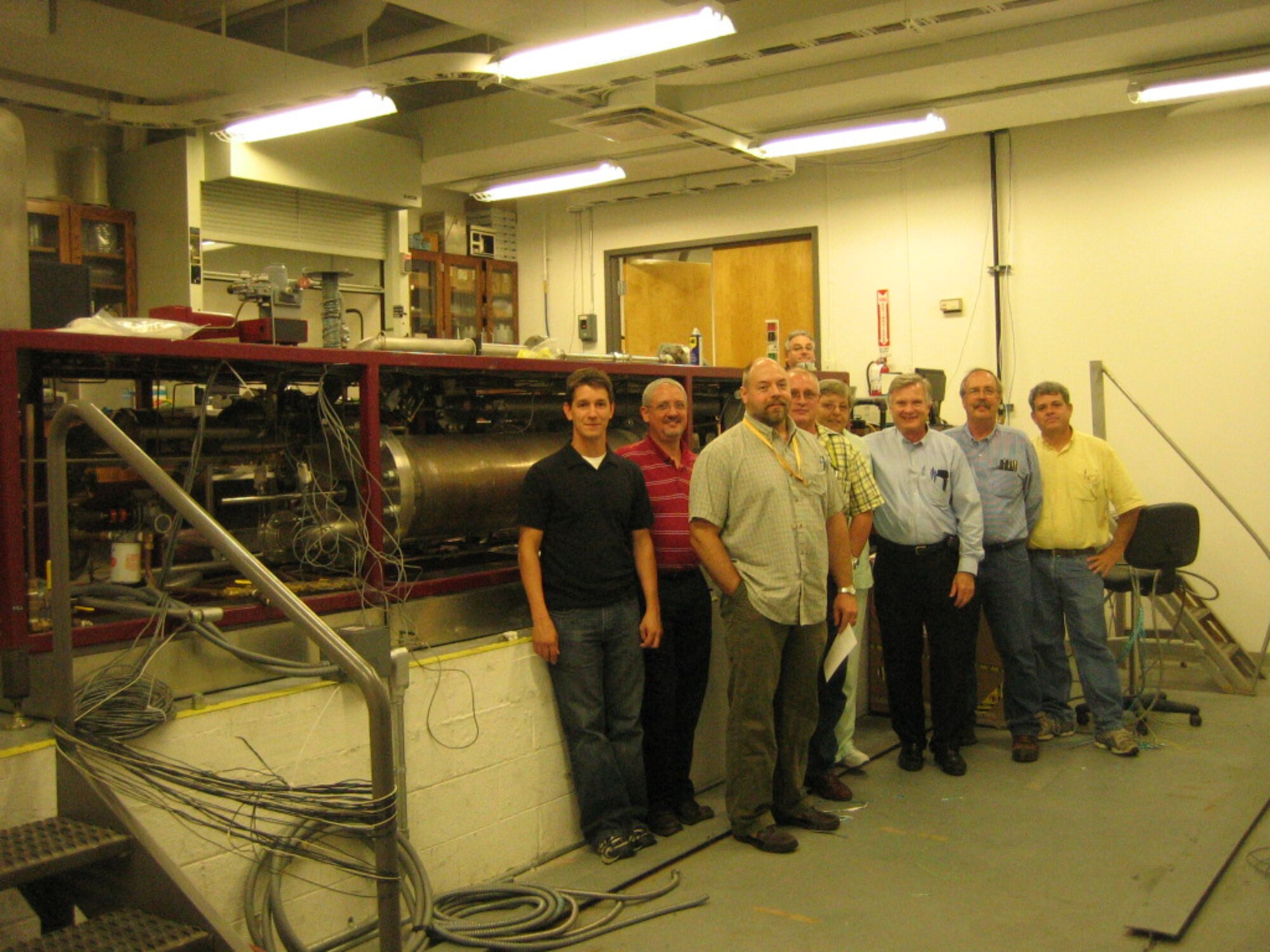 From left to right: Jeremy Latsko, U.S. Air Force Metrology and Calibration; Russell Kauffman, U.S. Army Primary Standards Laboratory; Wes England, U.S. Army Primary Standards Laboratory; Michael Vickers, U.S. Army Primary Standards Laboratory; Judy Burden, U.S. Army PD TMDE; John Ball, UAH and U.S. Army PD TMDE; James Winchester, Aerospace Testing Alliance, Inc., and Joel Davenport, University of Tennessee Space Institute, pose for a group photo during a joint services group meeting adjacent to the turbine flow meter calibrator loaned to AEDC by Vandenberg AFB, Calif., (official designation is PCLCE-350) July 7, 2009. (Photo provided)