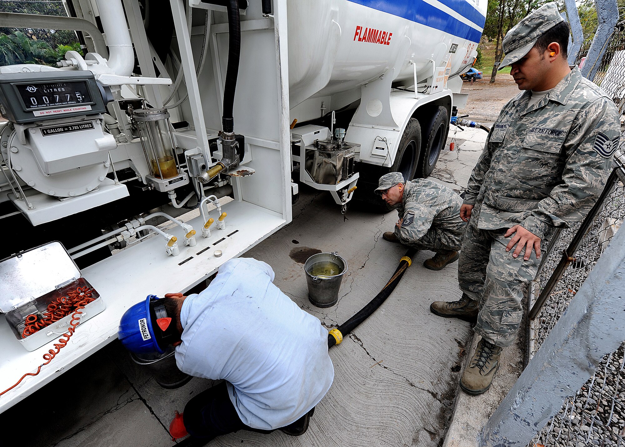 Master Sgt. Michael Raffa and Tech. Sgt. Filiberto Rodriguez, 571st Mobility Support Advisory Squadron fuels air advisors, look on as a Honduran contractor prepares the container for a fuel sample, in Tegucigalpa, Honduras, Feb. 13.  The MSAS Airmen, representing 15 Air Force specialties, are  working side-by-side with Honduran Air Force members in developing the seven core competencies of air base defense, air traffic control, aircraft maintenance, aircrew survival, communications, generator maintenance and safety.   (U.S. Air Force photo by Tech. Sgt. Lesley Waters)