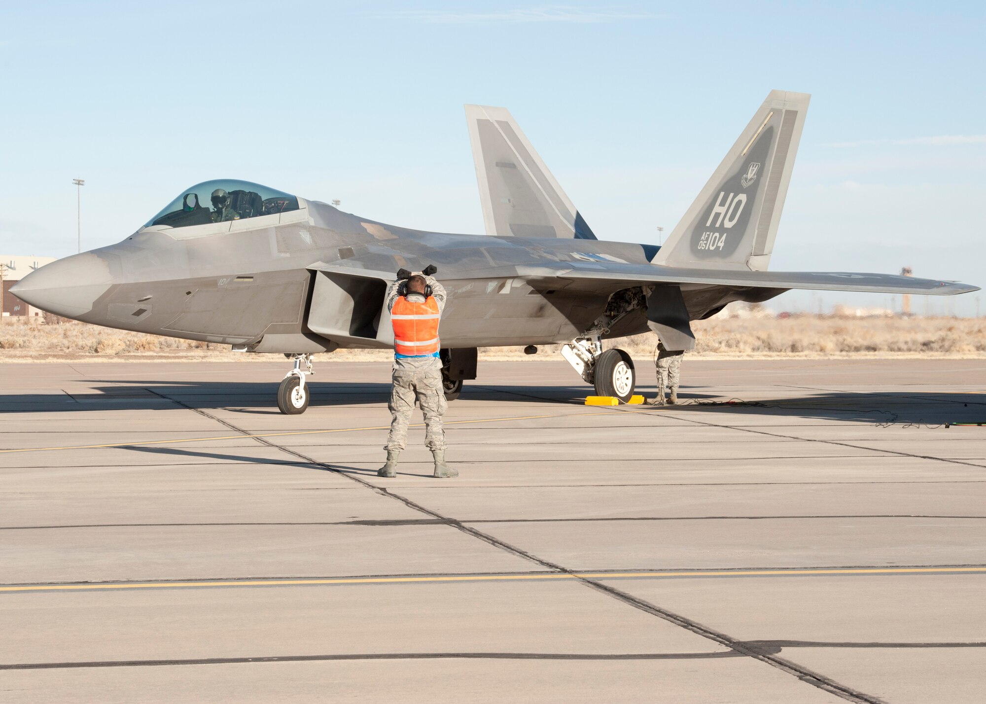 A 7th Aircraft Maintenance Unit crew chief marshals an F-22 Raptor Feb. 13 at Holloman Air Force Base, N.M. F-22 crew chiefs from the 7th AMU are responsible for nearly every aspect of the aircraft including refueling, defueling, launch, recovery, hydraulics, brakes, tires, flight control surfaces, inspections, engines, and engine runs for trouble shooting purposes. (U.S. Air Force photo by Airman 1st Class Siuta B. Ika/Released)