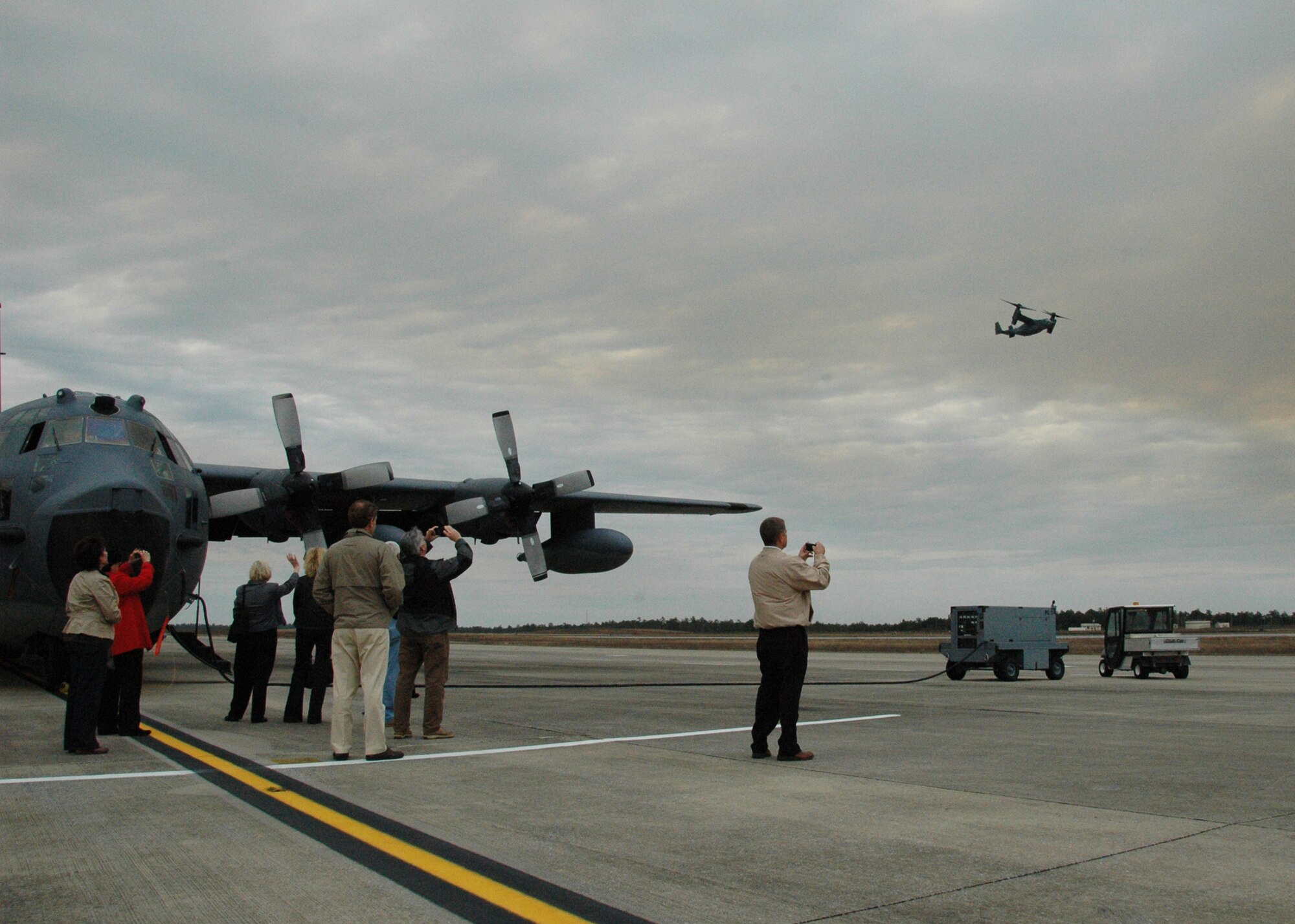 While touring an MC-130E aircraft on the Duke Field flightline Feb. 15, honorary commanders from Eglin AFB and Duke take opportune photos of a passing CV-22 Osprey on a training flight from nearby Hurlburt Field, Fla. The honorary commanders for dozens of Eglin and Duke organizations toured both bases to gain a better understanding of how their Airmen perform their respective missions for national defense.  (U.S. Air Force photo/Dan Neely)
