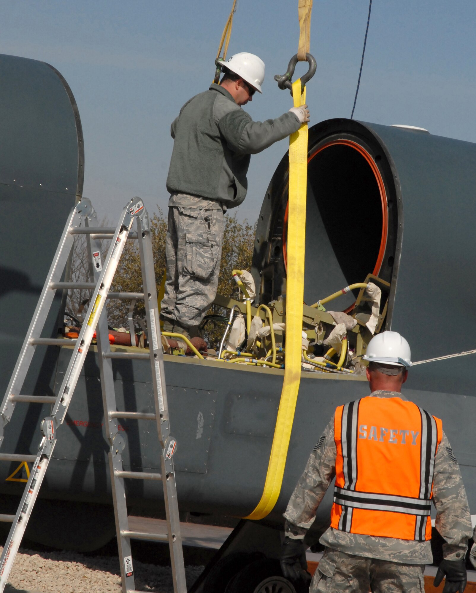 GOODFELLOW AIR FORCE BASE, Texas - Tech. Sgt.  James Fountain, 17th Training Wing Safety, watches as Staff Sgt. Brandon Gambrel, 76th Aircraft Maintenance Group, Tinker Air Force Base, Okla., adjusts and stabilizes a rope on the body of the RQ-4 Global Hawk preparing it for hoisting during its assembly Feb. 8. Goodfellow is one of only two bases to receive an RQ-4 Global Hawk in the history of the Air Force. (U.S. Air Force photo/Senior Airman Anne Gathua) 