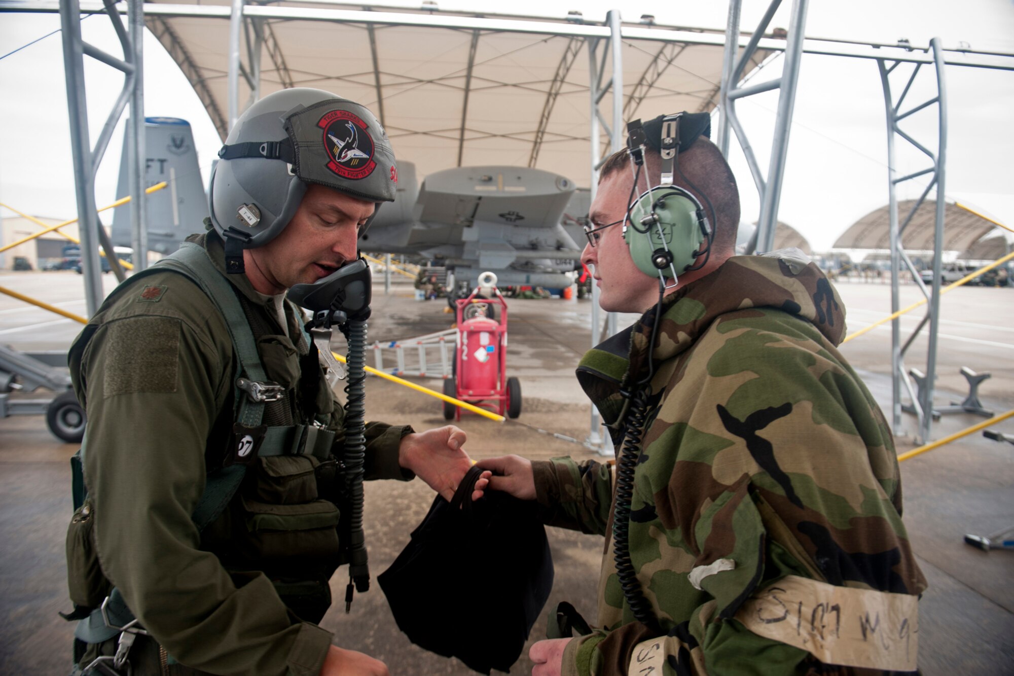 U.S. Air Force Maj. Matthew Clausen, 23d Fighter Group A-10C Thunderbolt II pilot, hands flight equipment to Senior Airman Joshua Vaughan, 23d Aircraft Maintenance Squadron crew chief, before takeoff in an A-10 during an operational readiness exercise Feb. 16, 2012, at Moody Air Force Base, Ga. 
Pilots and crew chiefs stay in constant communication with each other during pre-flight checks to ensure maximum safety of personnel and assets. (U.S. Air Force photo by Staff Sgt. Jamal D. Sutter/Released)  
