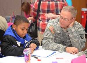 U.S. Army Maj. Gen. Richard C. Longo, United States Army Training and Doctrine Command, deputy commanding general for Initial Military Training, helps James Owens with his homework at the Dinner for Families of Deployed event at the Fort Eustis Regimental Chapel Feb. 14. More than 25 volunteers provided dinner and various activities for families throughout the Eustis military community. (U.S. Air Force photo by Staff Sgt. Antoinette Gibson/Released)