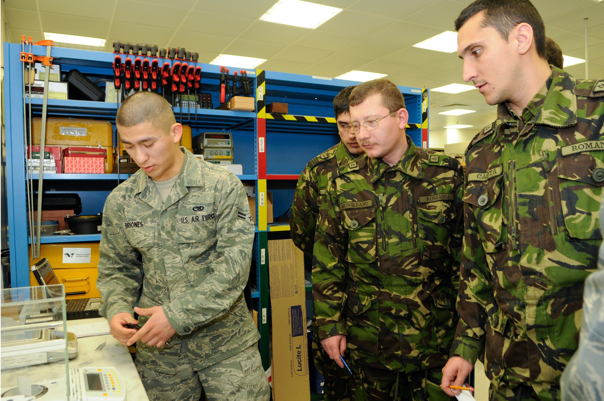 U.S. Air Force Airman 1st Class Jesus Briones places a test strip of paper on to a scale during a  Precision Measurement Equipment Laboratory tour for Romanian Air Force members, Feb. 9, 2012. (U.S. Air Force photo by Senior Airman Stephen J. Otero)