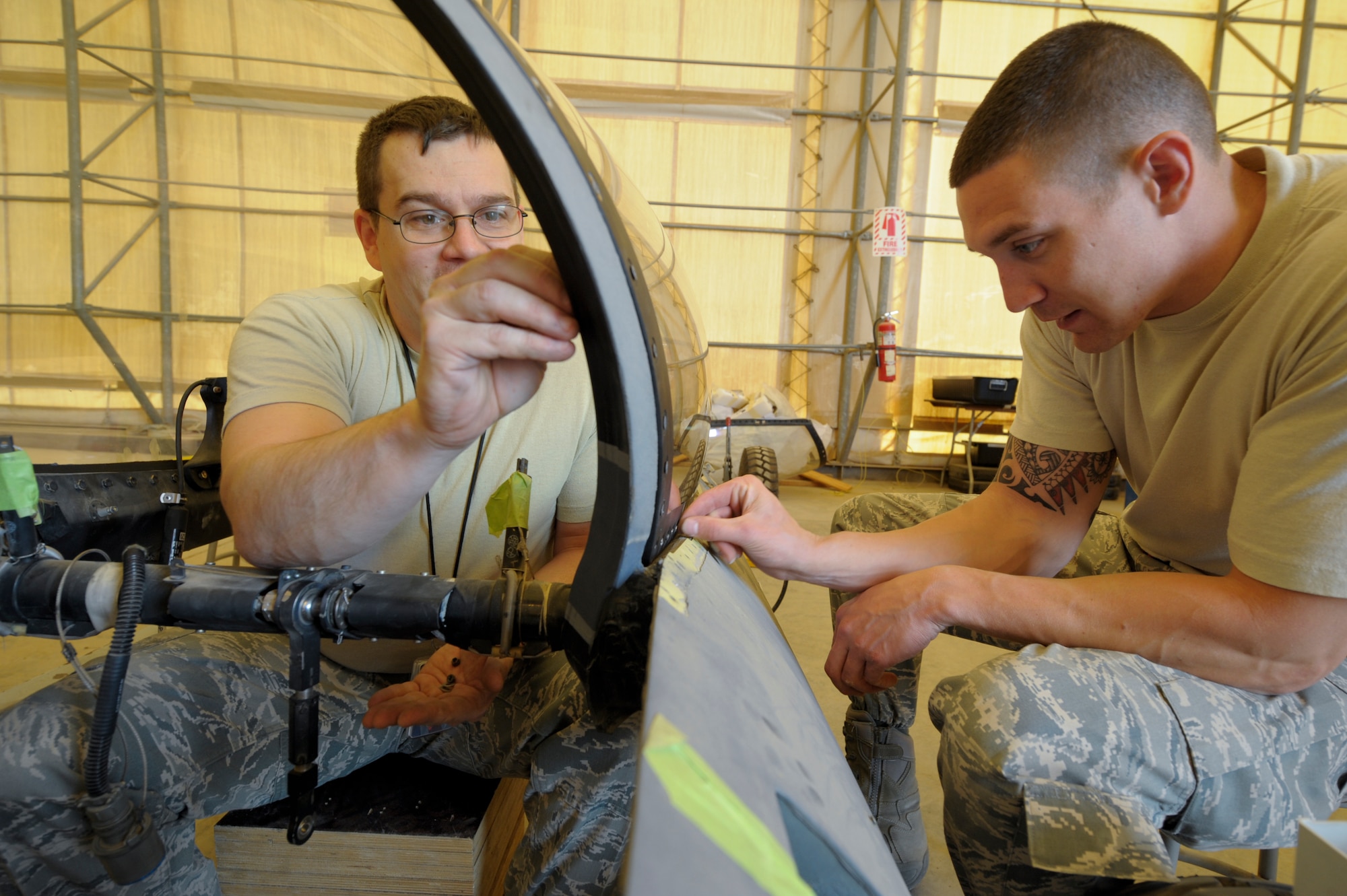 Staff Sgt. John Self and Senior Airman Matthew Goff, 332nd Expeditionary Maintenance Squadron egress flight members, place bolts into an F-16 Fighting Falcon canopy frame at an undisclosed location in Southwest Asia, Feb. 19, 2012. The canopy frame is connected to the transparency with 127 nuts and bolts. Self is a native of Atlanta, Texas, and Goff is a native of Williamson, N.C. Both are deployed from Shaw Air Force Base, S.C. (U.S. Air Force photo by Staff Sgt. Joshua J. Garcia/Released)