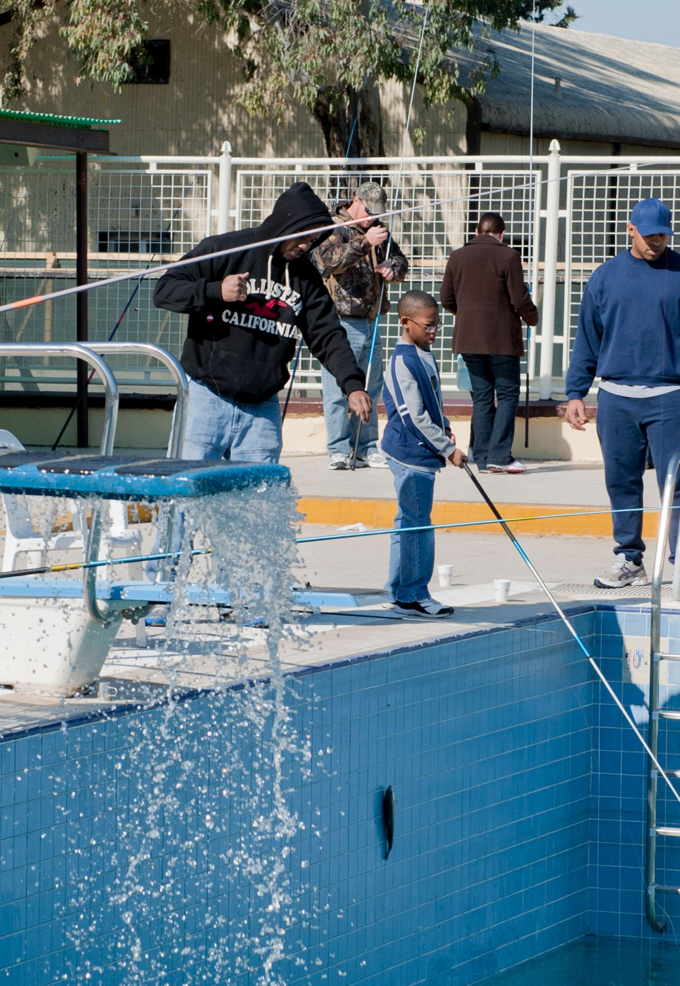 Ramon Holmes, left, husband of Airman 1st Class Shannon Holmes of the 39th Security Forces Squadron, catches a fish during the outdoor-recreation-center sponsored fishing rodeo at the base pool Feb. 19, 2012, at Incirlik Air Base, Turkey. The rodeo began Feb. 18 with 500 fish. More than 300 people participated during the three-day event. (U.S. Air Force photo by Senior Airman Anthony Sanchelli/Released) 
