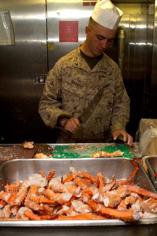 Machine-gunner Lance Cpl. Alec Maddox chops crab legs for a Mardi Gras dinner aboard the amphibious transport dock ship USS New Orleans here Feb. 21. The 19-year-old Salt Lake City native serves with Company L, one of three rifle companies with Battalion Landing Team 3/1. The landing team is the ground combat element for the 11th Marine Expeditionary Unit. The unit is deployed as part of the Makin Island Amphibious Ready Group, a U.S. Central Command theater reserve force. The group is providing support for maritime security operations and theater security cooperation efforts in the U.S. Navy's 5th Fleet area of responsibility.