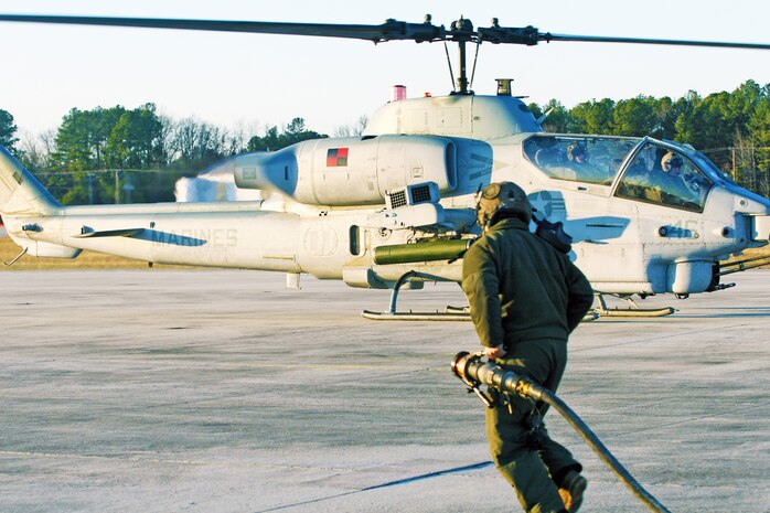 Cpl. Theodore M. Young, crew chief, runs with the fuel hose used in the tactical bulk fuel delivery system to refuel the AH-1W Cobra. Marines with Marine Heavy Helicopter Squadron 461 conducted training setting up a Forward Arming and Refueling Point at Blackstone Army Airfield, Dec. 13.