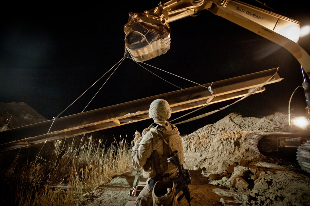 First Lieutenant Matt Paluta, the commander of Bridge Platoon and a native of Cincinnati, Ohio, helps move a 40-foot steel I-beam into place with the help of an excavator during the construction of a bridge near Combat Outpost Rankel in the district of Garmsir, Helmand province, Jan. 29. The Marines of Bridge Platoon endured a 5-day convoy in order to replace a temporary bridge with a more permanent structure that would increase mobility for Marines operating in the area.