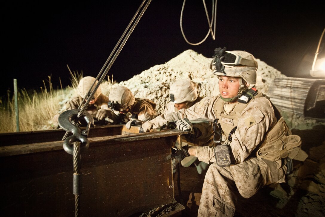 Marines with Bridge Platoon, Alpha Company, 9th Engineer Support Battalion help move a 40-foot steel I-beam into place with the help of an excavator during the construction of a bridge near Combat Outpost Rankel in the district of Garmsir, Helmand province, Jan. 29. The Marines of Bridge Platoon endured a 5-day convoy in order to replace a temporary bridge with a more permanent structure that would increase mobility for Marines operating in the area.