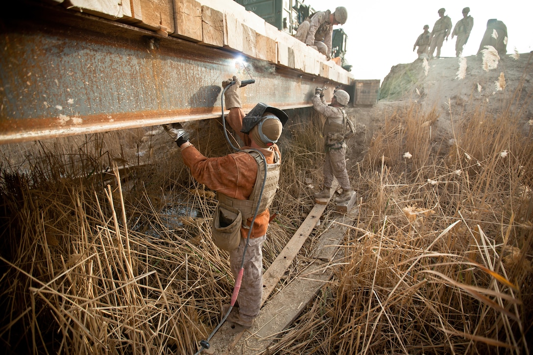 Lance Cpl. Dan Schergen, a metal worker with Support Company, 9th Engineer Support Battalion and a native of Valparaiso, Ind., welds a bolt into place during the construction of a bridge near Combat Outpost Rankel in the district of Garmsir, Helmand province, Jan. 29. The Marines of Bridge Platoon, Alpha Company, 9th Engineer Support Battalion endured a 5-day convoy in order to replace a temporary bridge with a more permanent structure that would increase mobility for Marines operating in the area.