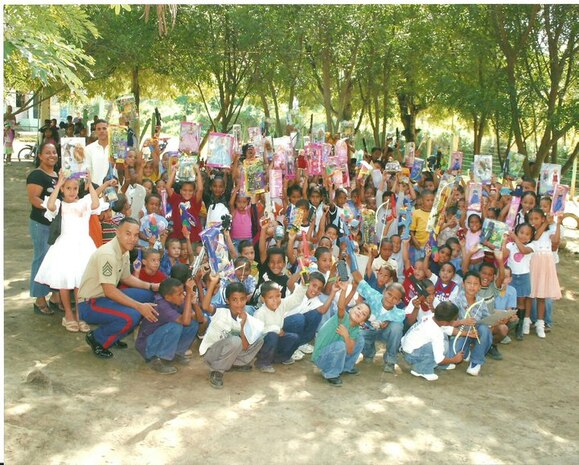 SAN JOSE ADENTRO, Santiago - 1st Lt. Jose Quezada, bottom left, then a staff sergeant., an air support control officer with Marine Air Support Squadron 3 and a Santiago, Dominican Republic, native, poses with children from the Dominican Republic, after distributing toys Dec. 23, 2006. The Quezada family approved several schools' sponsorship for this upcoming holiday season.
