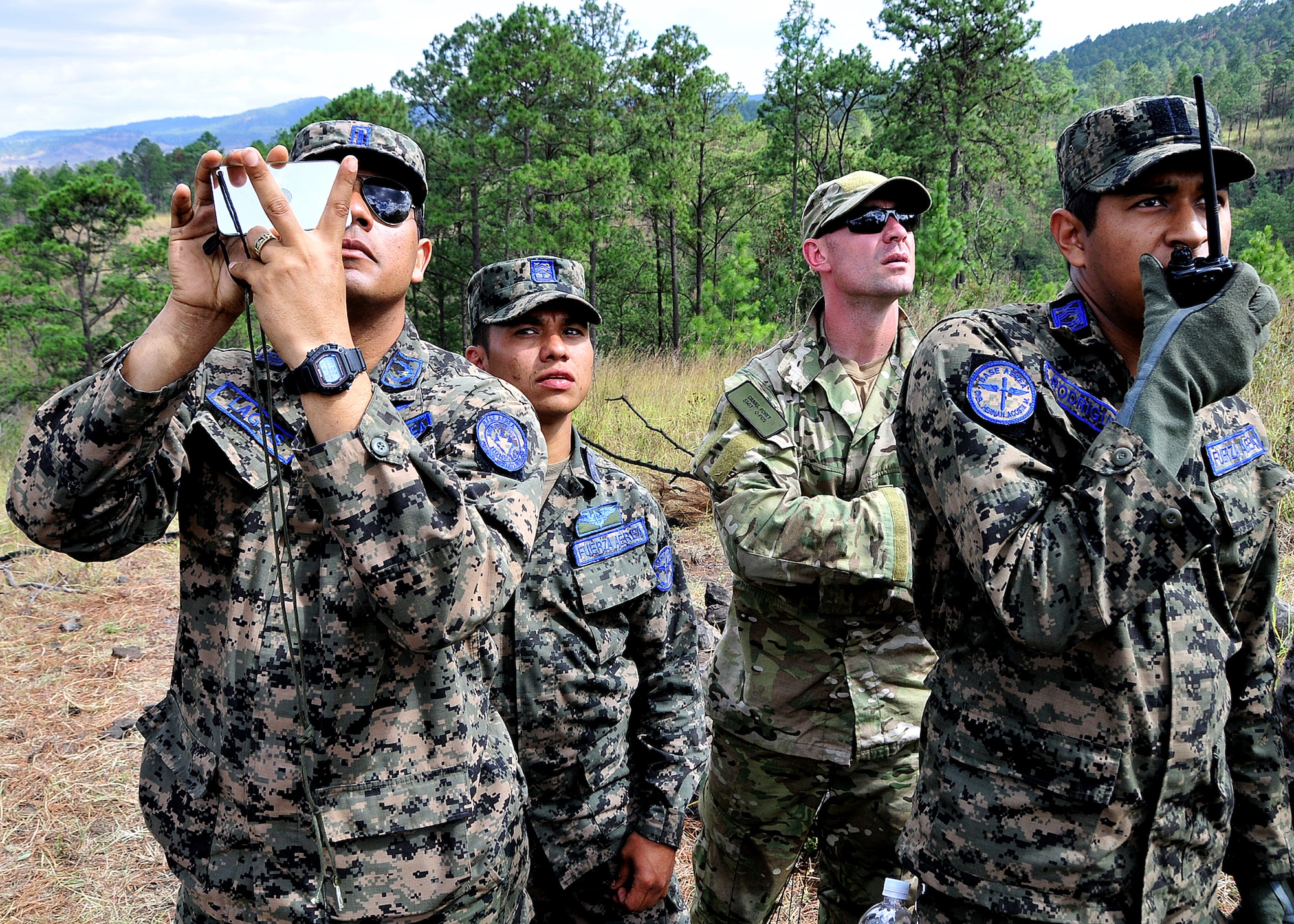 Staff Sgt. Daniel Foret, 571st Mobility Support Advisory Squadron Survival, Evasion, Resistance and Escape specialist air advisor, looks on as members of the Honduran Air Force air crew practice signaling and communicating their position to the pilot during the vectoring application of the aircrew survival seminar at Tamara, Honduras, Feb. 15.  (U.S. Air Force photo by Tech. Sgt. Lesley Waters)