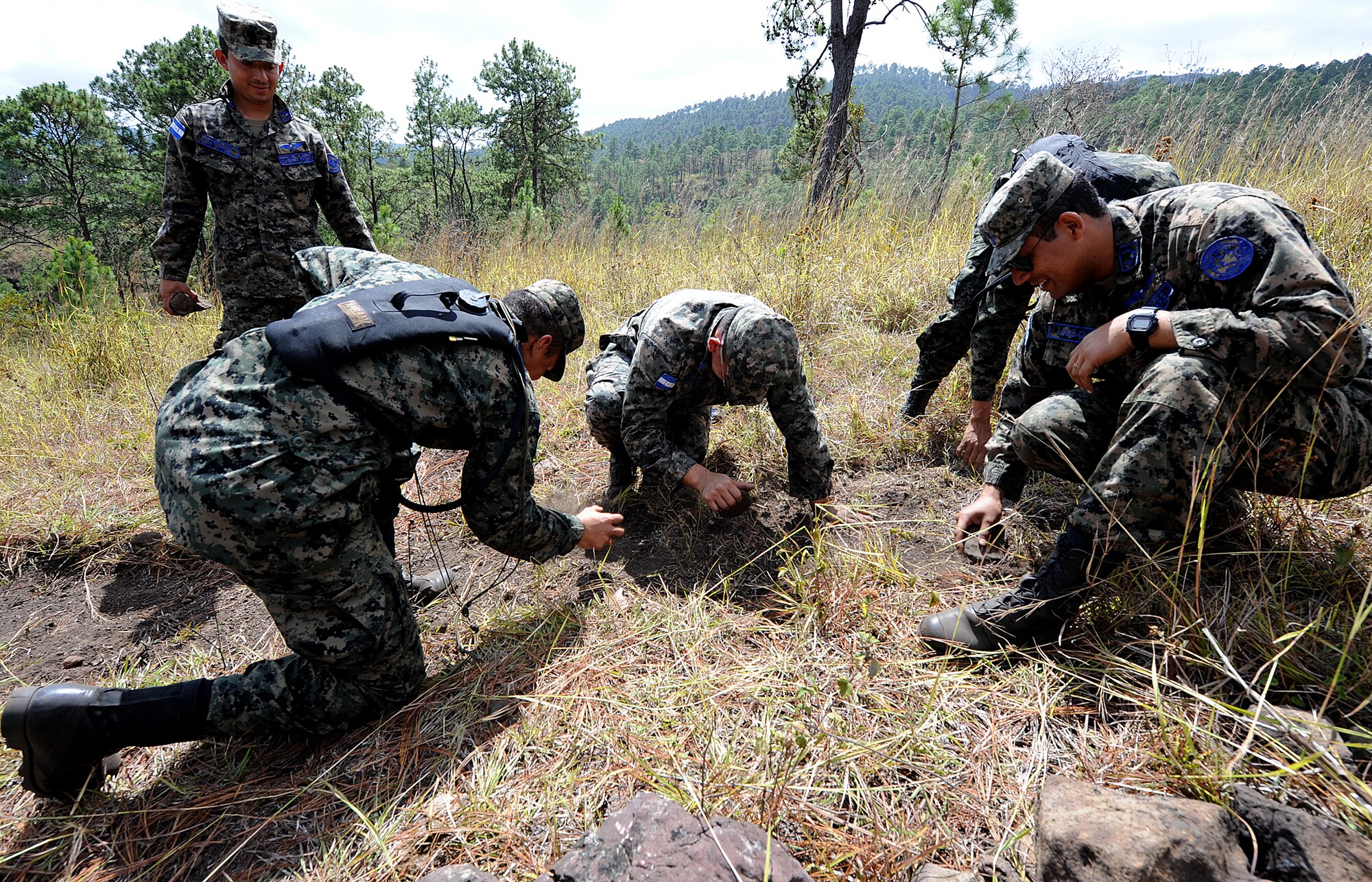 Honduran Air Force air crew members and soldiers from the Honduran army's unit TESON clear an area by making a "V" in the ground to help an aircraft locate their position during the vectoring application of the aircrew survival seminar at Tamara, Honduras, Feb. 15.  TESON stands for Tropas Especiales para Operaciones de Selva y Nocturnas, which is their equivalent to the U.S. Army Rangers.  (U.S. Air Force photo by Tech. Sgt. Lesley Waters)