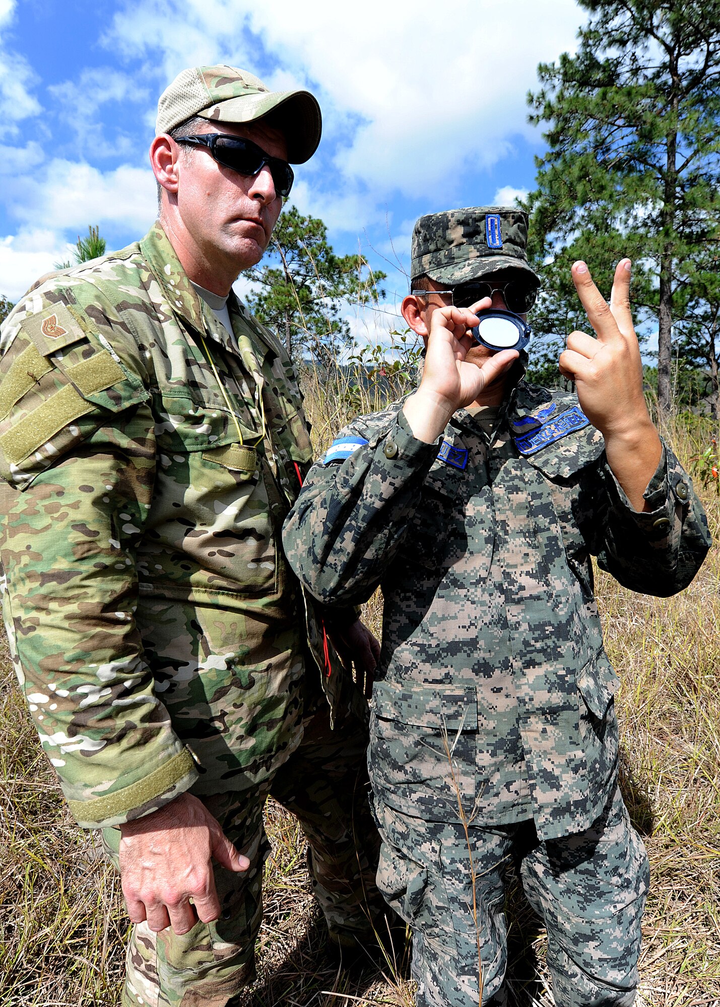 Tech. Sgt. Troy Daland, 571st Mobility Support Advisory Squadron Survival, Evasion, Resistance and Escape specialist air advisor, looks on as a Honduran Air Force pilot practices signaling with a mirror during the field application of the aircrew survival seminar at Tamara, Honduras, Feb. 15.  (U.S. Air Force photo by Tech. Sgt. Lesley Waters)