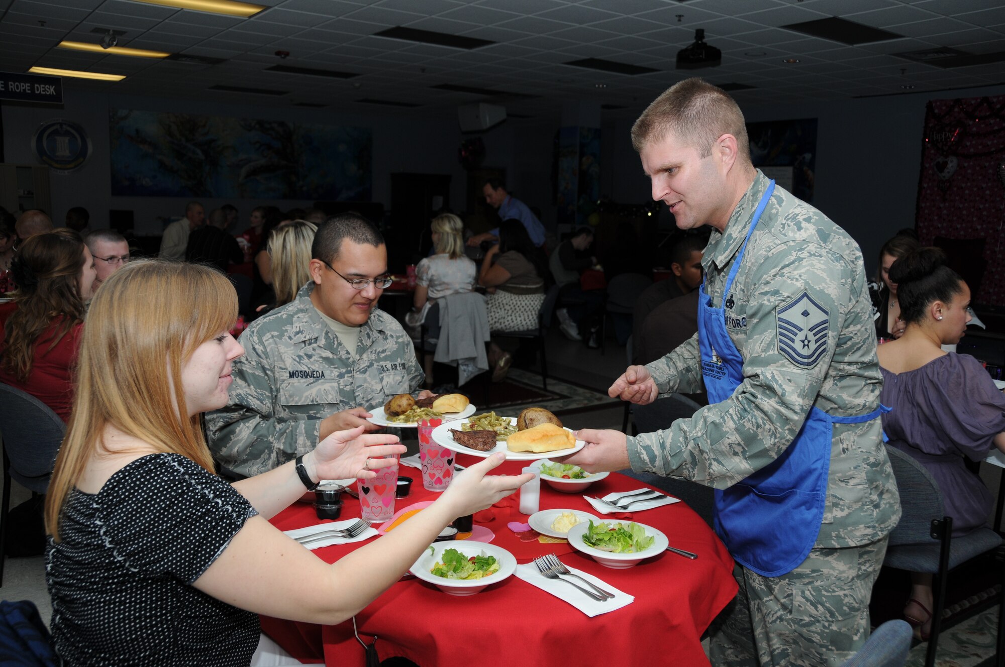Heather Mosqueda and her husband, Airman 1st Class Jonathan Mosqueda, 338th Training Squadron, are served their meal by Master Sgt. Ryan Bienvenu, 336th TRS First Sgt. during the family night dinner for training students and their spouses Feb. 15, 2012, at the Levitow Training Support Facility, Keesler Air Force Base, Miss.  The meal was prepared by the airmen and family readiness center staff and served by members of the Key Spouse group, squadron commanders and first sergeants.  (U.S. Air Force photo by Kemberly Groue)