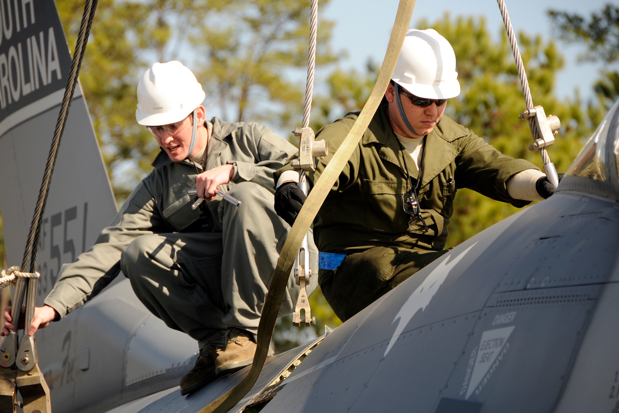Airman 1st Class Casey Gray and Technical Sgt. Bronson Priebe, crew chiefs with the 169th Aircraft Maintenance Squadron at McEntire Joint National Guard Base, S.C., respond to a simulated aircraft mishap with a crashed F-16 fighter jet and UH-60 Black Hawk helicopter during a Crash, Damaged, Destroyed Aircraft Recovery (CDDAR) exercise on January 31, 2012.  A1C Gray and TSgt. Priebe connect straps to the F-16 jet so that it may be connected to a crane and transported from the accident sight. The training was important for all personnel involved due to the reality of the scenario, with the base sharing both air frames.
(SCANG photo by TSgt. Caycee Cook)
