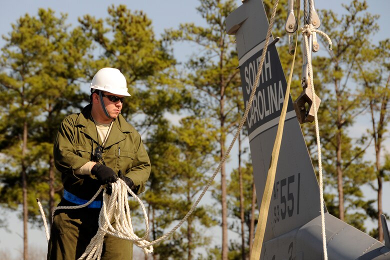 Technical Sgt. Bronson Priebe, a crew chief with the 169th Aircraft Maintenance Squadron at McEntire Joint National Guard Base, S.C., responds to a simulated aircraft mishap with a crashed F-16 fighter jet and UH-60 Black Hawk helicopter during a Crash, Damaged, Destroyed Aircraft Recovery (CDDAR) exercise on January 31, 2012.  TSgt. Priebe prepares straps to be hooked onto the F-16 jet so that it may be connected to a crane and transported from the accident sight. The training was important for all personnel involved due to the reality of the scenario, with the base sharing both air frames.
(SCANG photo by TSgt. Caycee Cook)
