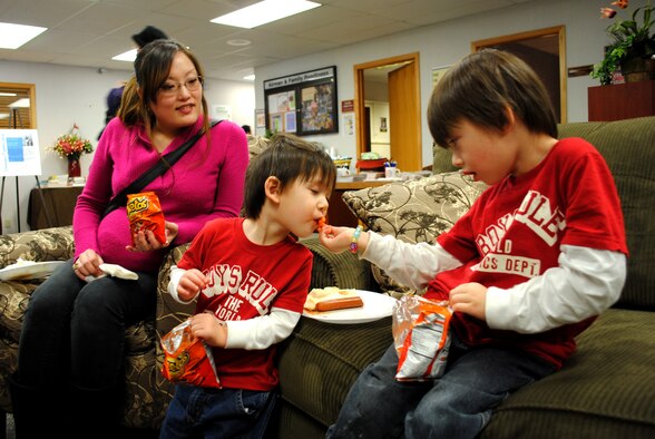 Mrs. Makiko David, military spouse to Master Sgt. Steven David an aircraft maintainer, watches as her four-year-old son, Winston, shares some of his snacks with his two-year-old brother Zachariah. Mrs. David was one several military spouses who along with their families took part in activities during the first day of Military Saves Week, which took place Feb. 21, 2012 at the Airman and Family Readiness Center at Grand Forks Air Force Base, N.D.  Guests were provided lunch for free. (U.S. Air Force photo/Senior Airman Luis Loza Gutierrez)