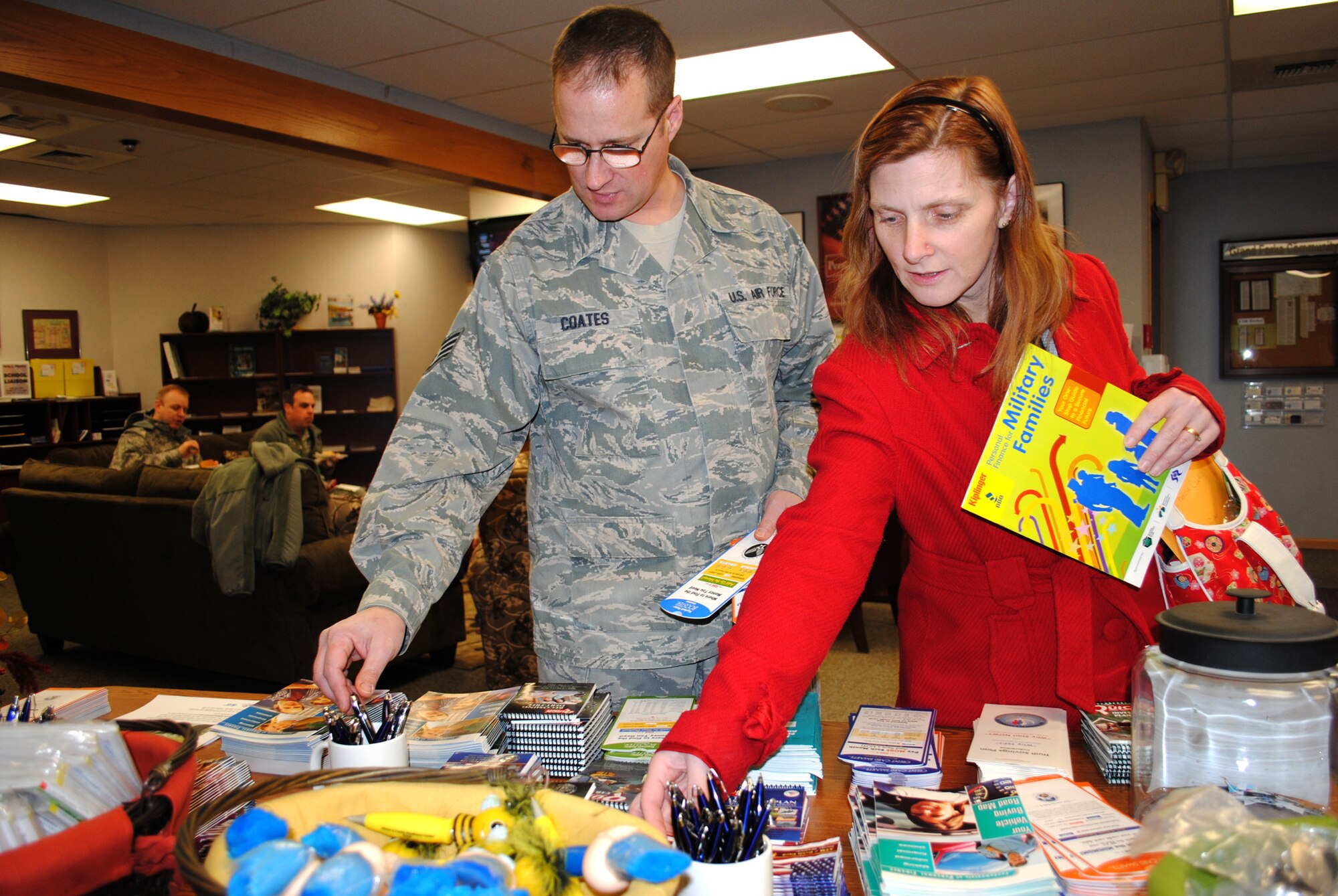 Staff Sgt. David Coates, 319th Civil Engineer Squadron snow control dispatcher, and his wife, Theresa reach for reading materials about retirement planning. The Coates were one of several military couples and families who attended the first day of Military Saves Week, which took place Feb. 21, 2012 at the Airmen and Family Center at Grand Forks Air Force Base, N.D. (U.S. Air Force photo/Senior Airman Luis Loza Gutierrez)