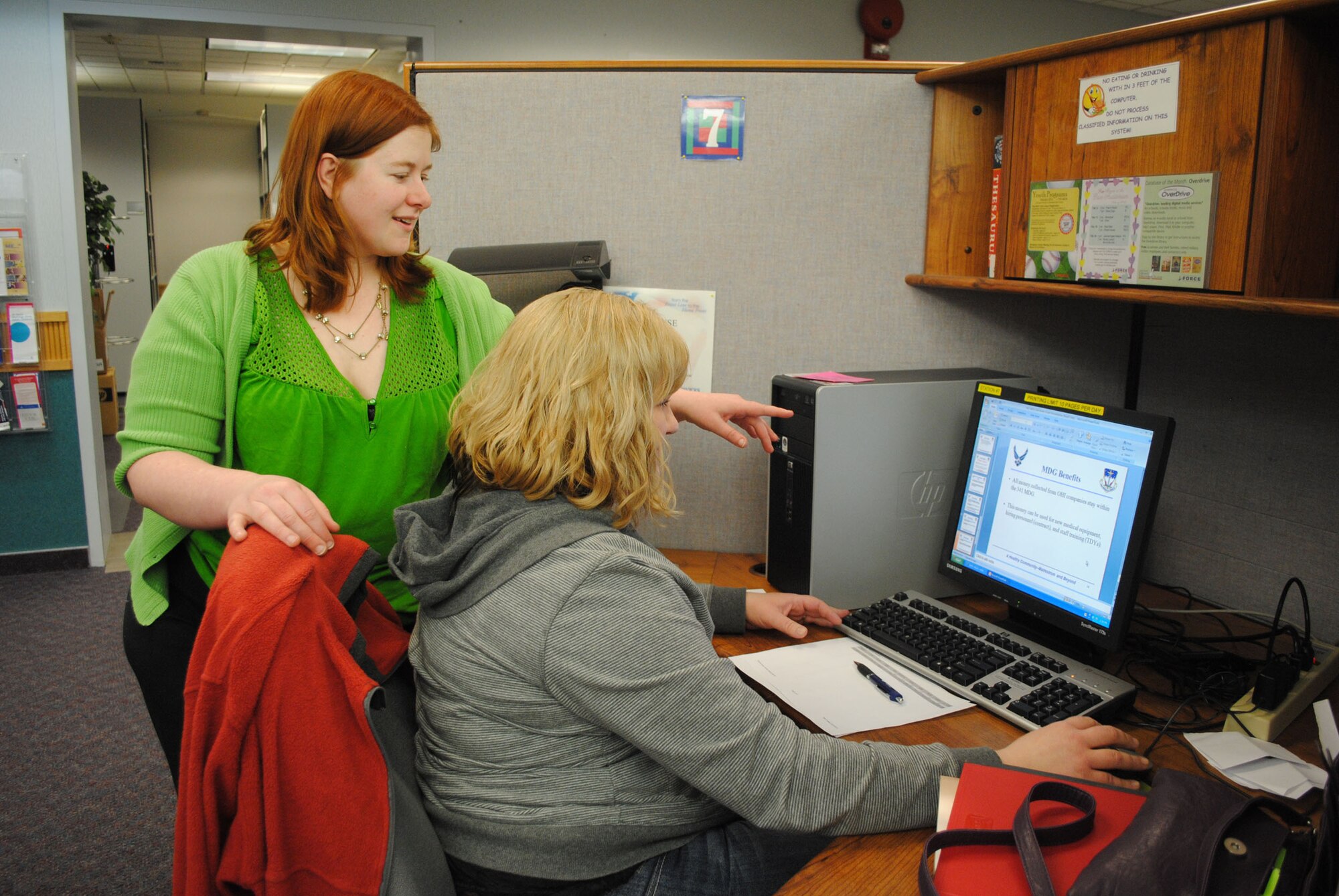 Kylea Minteer-Jacobs, 341st Force Support Squadron library technician, assists Emily Shelton, 341st Medical Operations Squadron domestic violence victim advocate, as she works on computer training at the library Feb. 13. (Courtesy photo)