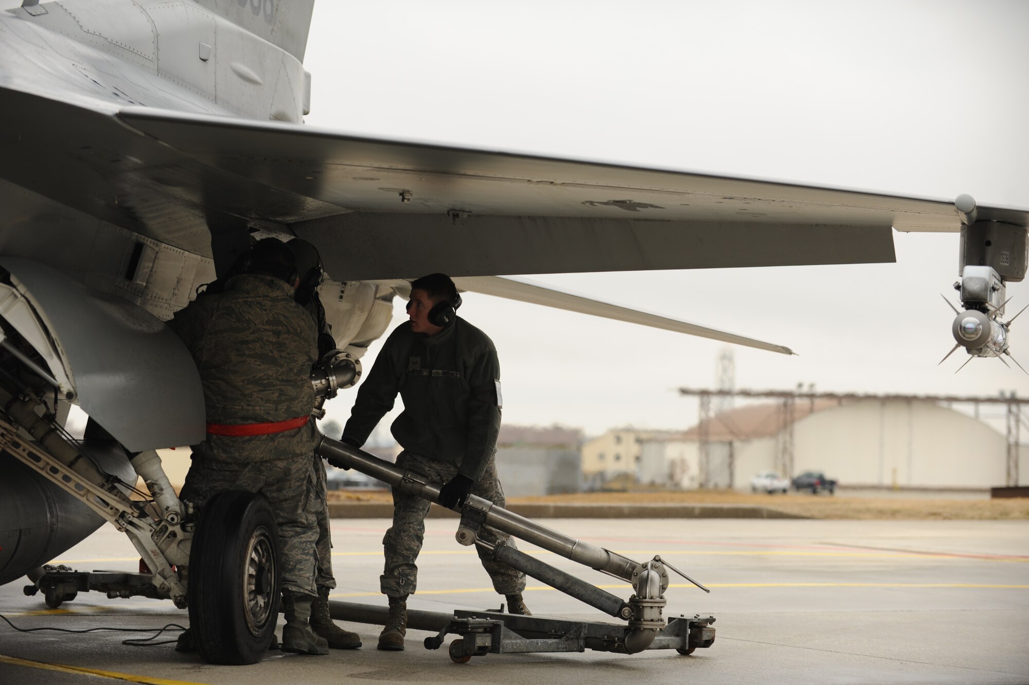 SPANGDAHLEM AIR BASE, Germany – Airmen from the 52nd Logistics Readiness Squadron and 52nd Aircraft Maintenance Squadron work together to lift a Type-4 hydrant system to refuel an F-16 Fighting Falcon during hot-pit refueling here Feb. 16. Hot-pit refueling saves time, manpower and equipment usage by using a Type-4 hydrant system to refuel active aircraft between training missions. Refueling still-running aircraft requires fewer Airmen and no refueling trucks because only two 52nd Logistics Readiness Squadron Fuels Distribution Airmen are needed to operate the hydrant system. (U.S. Air Force photo by Airman 1st Class Matthew B. Fredericks/Released) (U.S. Air Force photo by Airman 1st Class Matthew B. Fredericks/Released)