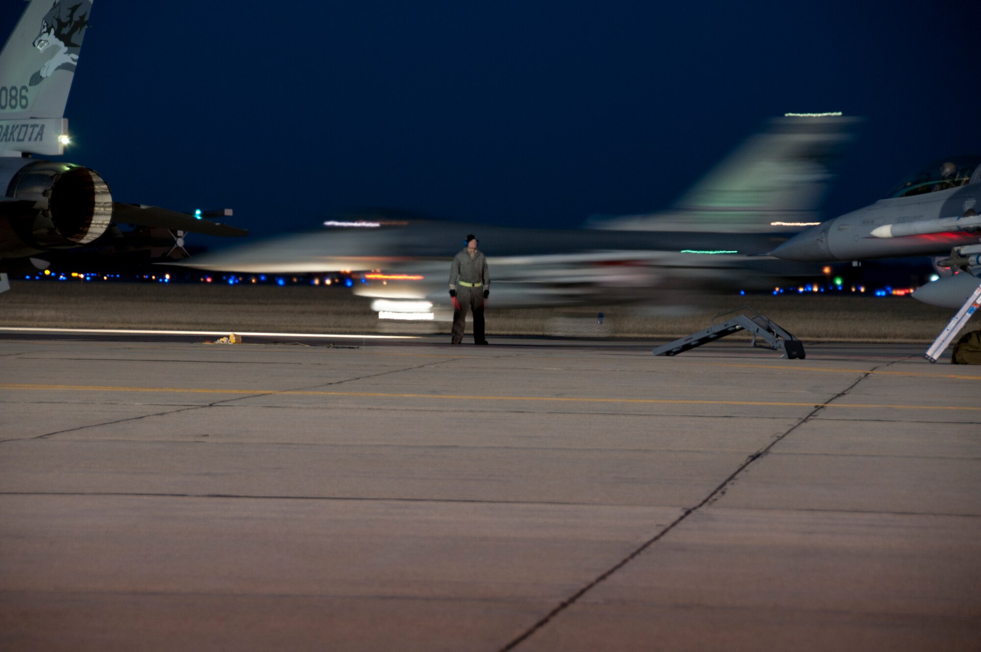 SIOUX FALLS, S.D. - As night falls on the ramp at Joe Foss Field, S.D., Technical Sgt. Ryan Bak, 114th Maintenance Group crew chief, prepares to assist with the taxi of an F-16 aircraft Feb. 16. The unit does night flying about once a month for a week in order to stay proficient with nighttime operations.(National Guard photo by Senior Master Sgt. Nancy Ausland)(Released)