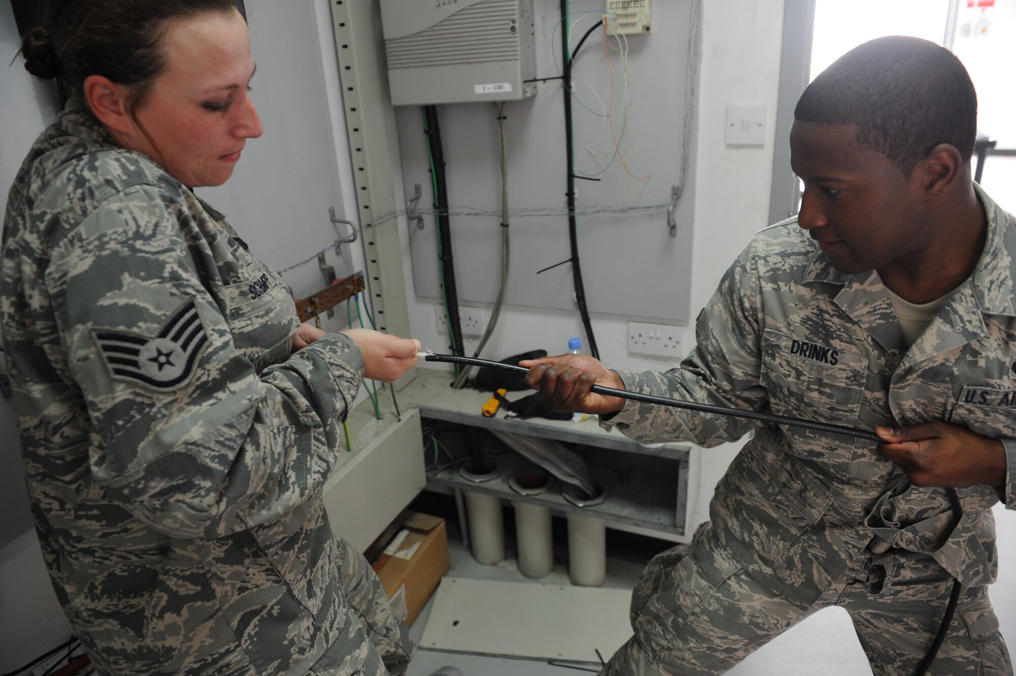 SOUTHWEST ASIA – Staff Sgt. Carla Schempp and Airman 1st Class Baron Drinks, 379th Expeditionary Communications Squadron cable technicians, pull to remove an outer sheath from an optical fiber line here Feb. 18, 2012. The actual fibers in the line are about 125 microns in diameter, roughly the size of a human hair, and the core of the fiber is only 9 microns in diameter. (U.S. Air Force photo/Staff Sgt. Nathanael Callon)
