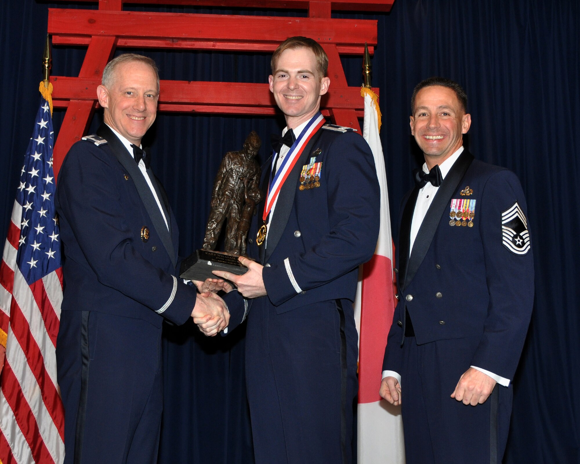 YOKOTA AIR BASE, Japan -- Col. Otto Feather, 374th Airlift Wing commander, and Chief Master Sgt. Richard Redman, acting 374th AW command chief master sergeant, presents Capt. William Powell, center, with the Kensei Company Grade Officer award at Yokota Air Base, Japan, Feb. 17, 2012. Powell is assigned to the 5th Air Force. (U.S. Air Force photo /Airman 1st Class Katrina R. Menchaca)