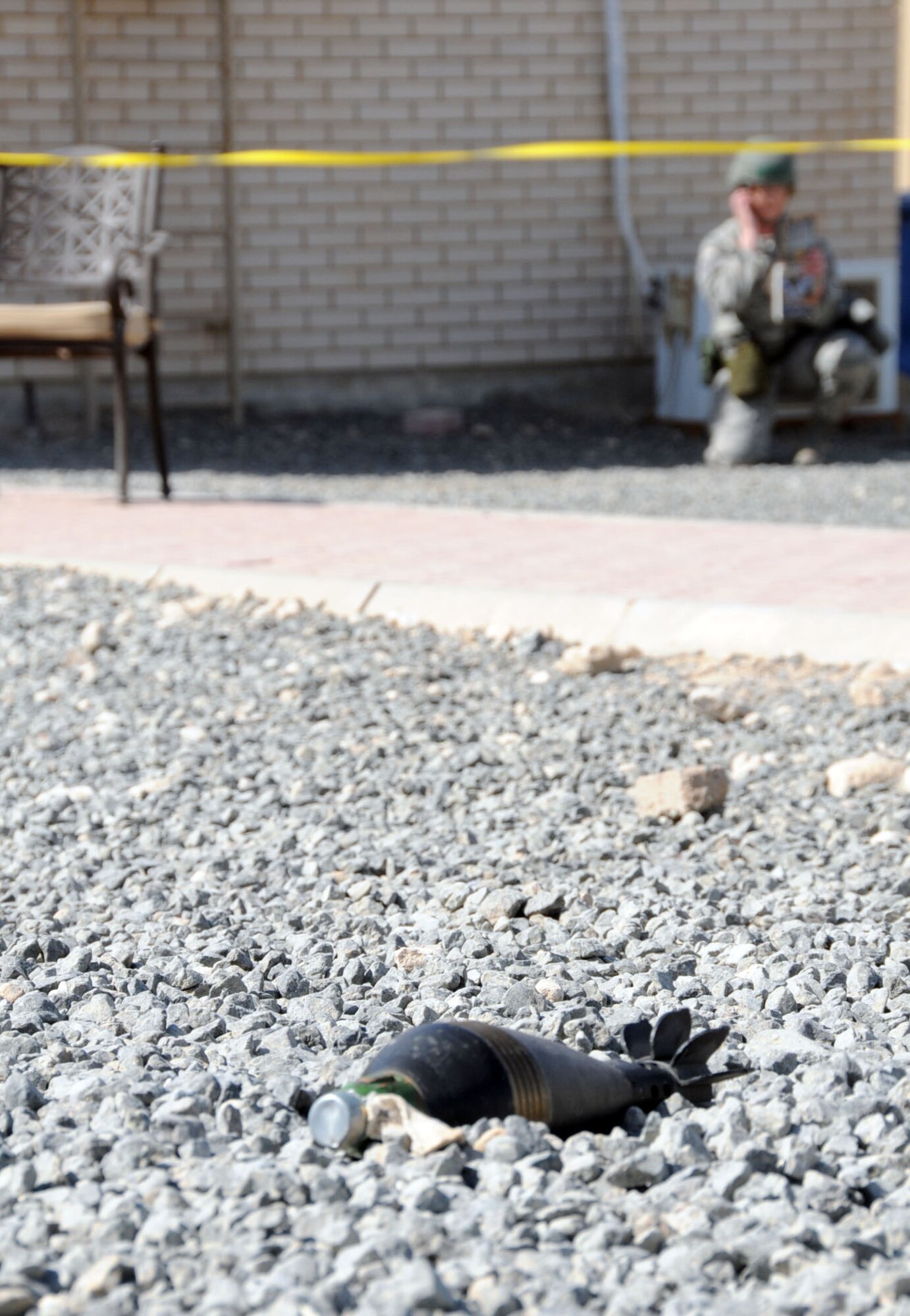 Simulated unexploded ordnance (UXO) sits idle in a cordoned off area as an Airman calls in their findings in an undisclosed location in Southwest Asia, Feb. 21, 2012. Members of the 386th Air Expeditionary Wing participated in a "bunker dive" exercise used to evaluate the overall readiness of base personnel and facilities while under a simulated attack. (U.S. Air Force photo by Staff Sgt. James Lieth/Released)