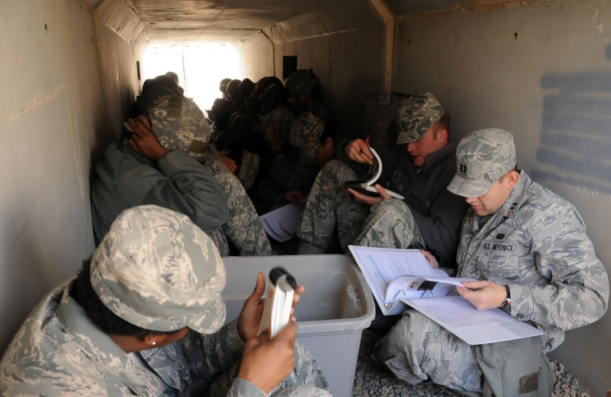 Members of the U.S. Air Force 386th Air Expeditionary Wing review their Airman’s Manuals and other information while taking cover in a bunker at an undisclosed location in Southwest Asia, Feb. 21, 2012. The 386th AEW conducted a "bunker dive" exercise to evaluate the overall readiness of base personnel and facilities while under a simulated attack. (U.S. Air Force photo by Staff Sgt. James Lieth/Released)