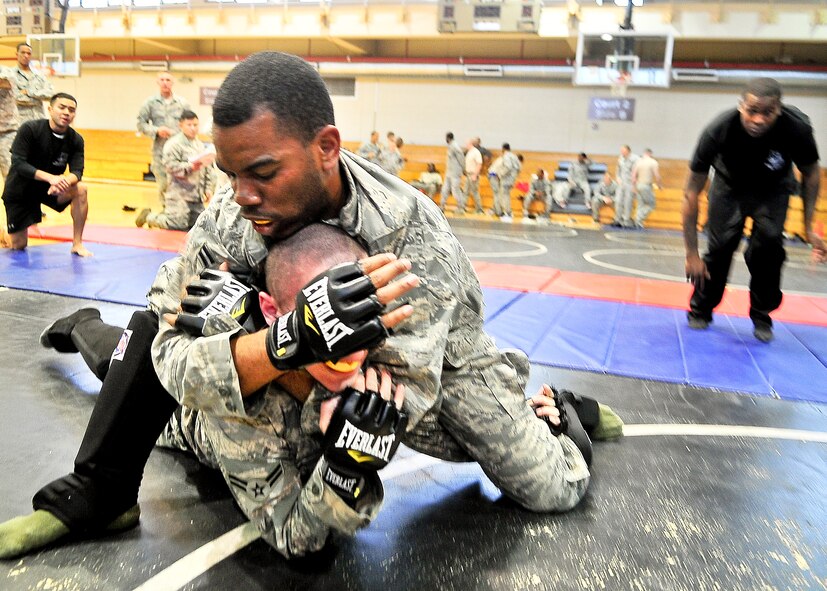 (Left) Senior Airman Antonio Johnson, 51st Security Forces Squadron combat readiness course instructor, speaks with both  Airman 1st Class Joseph Bird and Allen Perry, both 51st Security Forces Squadron members, during the combatives portion of a Combat Readiness Course here, Feb. 21, 2012. Airmen had eight different ways to score points that range from  take downs from the standing position, take downs from the seated position, passing the guard, sweeping, knee in the chest, reversal of submission, mounting and back mounting. (U.S. Air Force photo/Senior Airman Adam Grant)