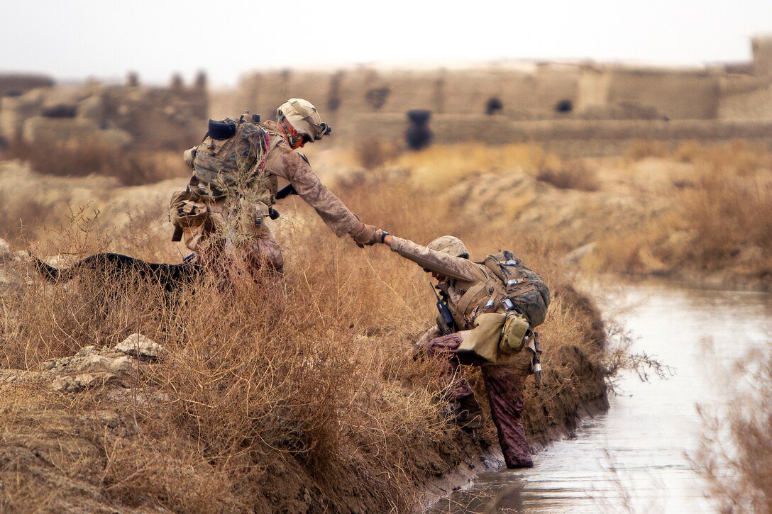 U.S. Marine Corps Lance Cpl. Brandon Mann helps Marine Corps Sgt. Guillermo Floresmartines out of a canal during a patrol around the villages of Sre Kala and Paygel in Helmand province, Afghanistan, Feb. 16, 2012. Mann is a military working dog handler and Floresmartines is an assistant squad leader, both assigned to Alpha Company, 1st Light Armored Reconnaissance Battalion. Mann's dog, Ty, is to the left of Mann's side.
