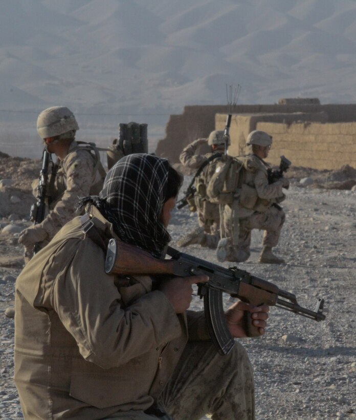 An Afghan National Civil Order Policeman with 1st Tolai, 4th Kandak, 3rd Brigade, posts security near the town of Wishtan, with the Marines of 2nd Squad, 1st Platoon, Lima Company, Feb. 22. The squad, part of 3rd Battalion, 7th Marine Regiment, patrolled parts of Wishtan and asked local people questions about the area. The Marines always patrol with atleast one ANCOP.