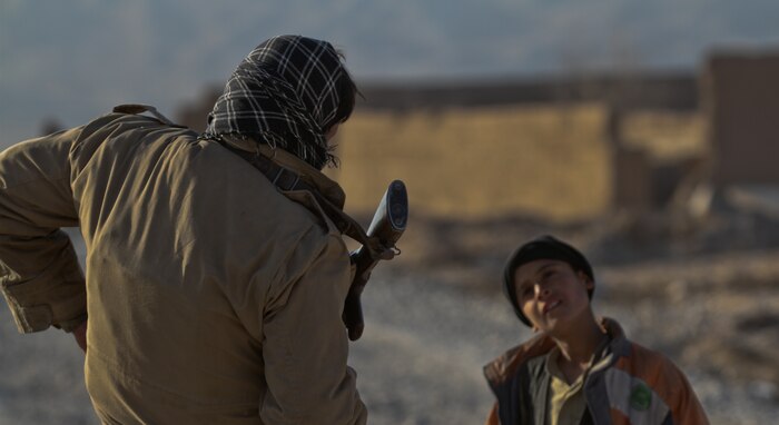 An Afghan National Civil Order Policeman with 1st Tolai, 4th Kandak, 3rd Brigade, answers questions from a curious Afghan child during a patrol in Wishtan, with Lima Company, 3rd Battalion, 7th Marine Regiment, Feb. 22. The Marines with 1st Platoon, Lima Co., with an ANCOP, talked with several local Afghans during the patrol. Marines said to have seen a difference in interactions with the locals from when they were here last year. Afghan children regularly approach the Marines and interaction with the Afghan people is an essential part of daily patrols.